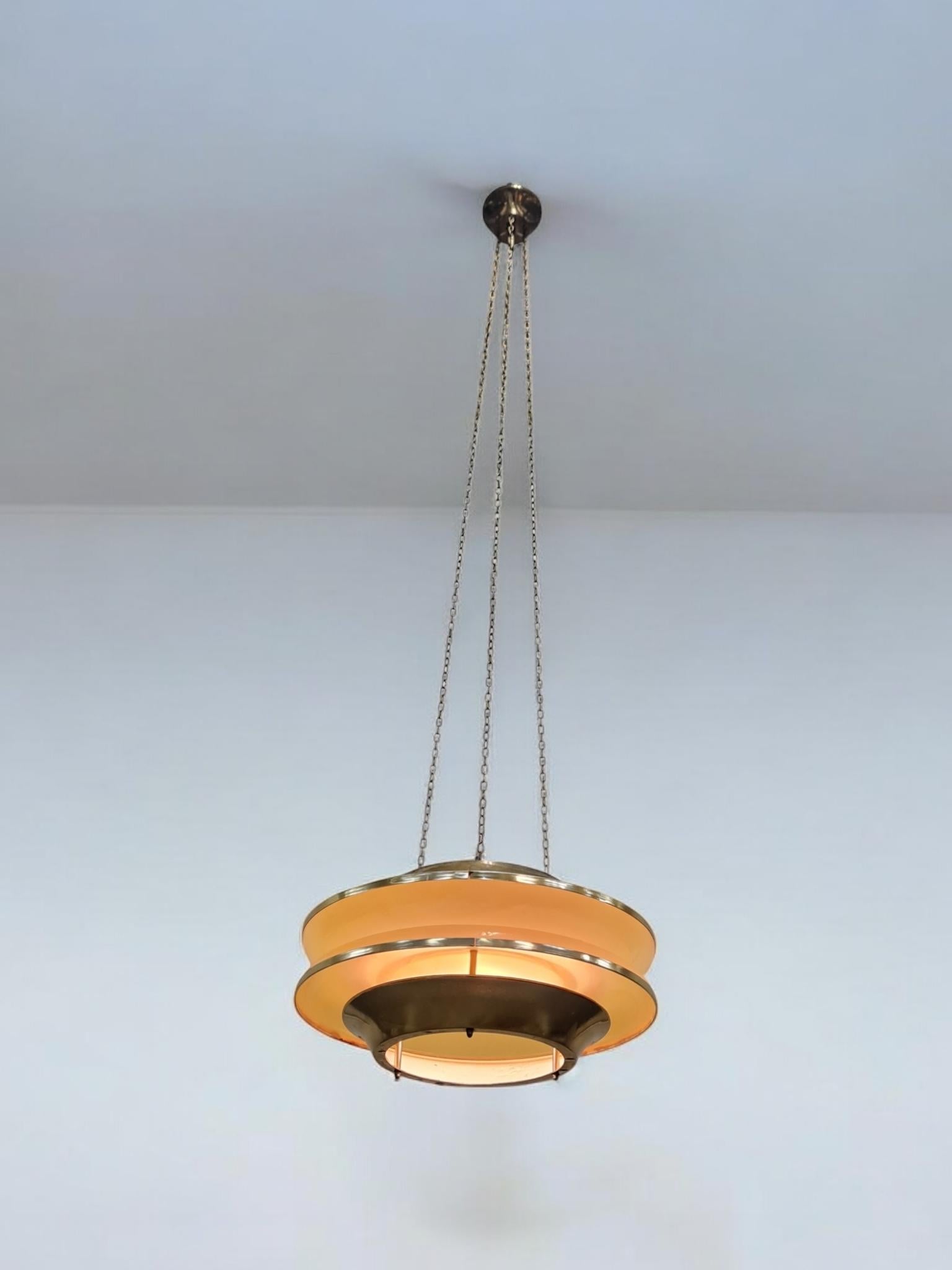 A modernistic slatted ceiling pendant by Finnish designer Kai Ruokonen (Finnmark) consisting of two opposing brass slates sandwiching two acrylic beige cylinders working as a light diffuser. A futuristic piece that not only suits space age
