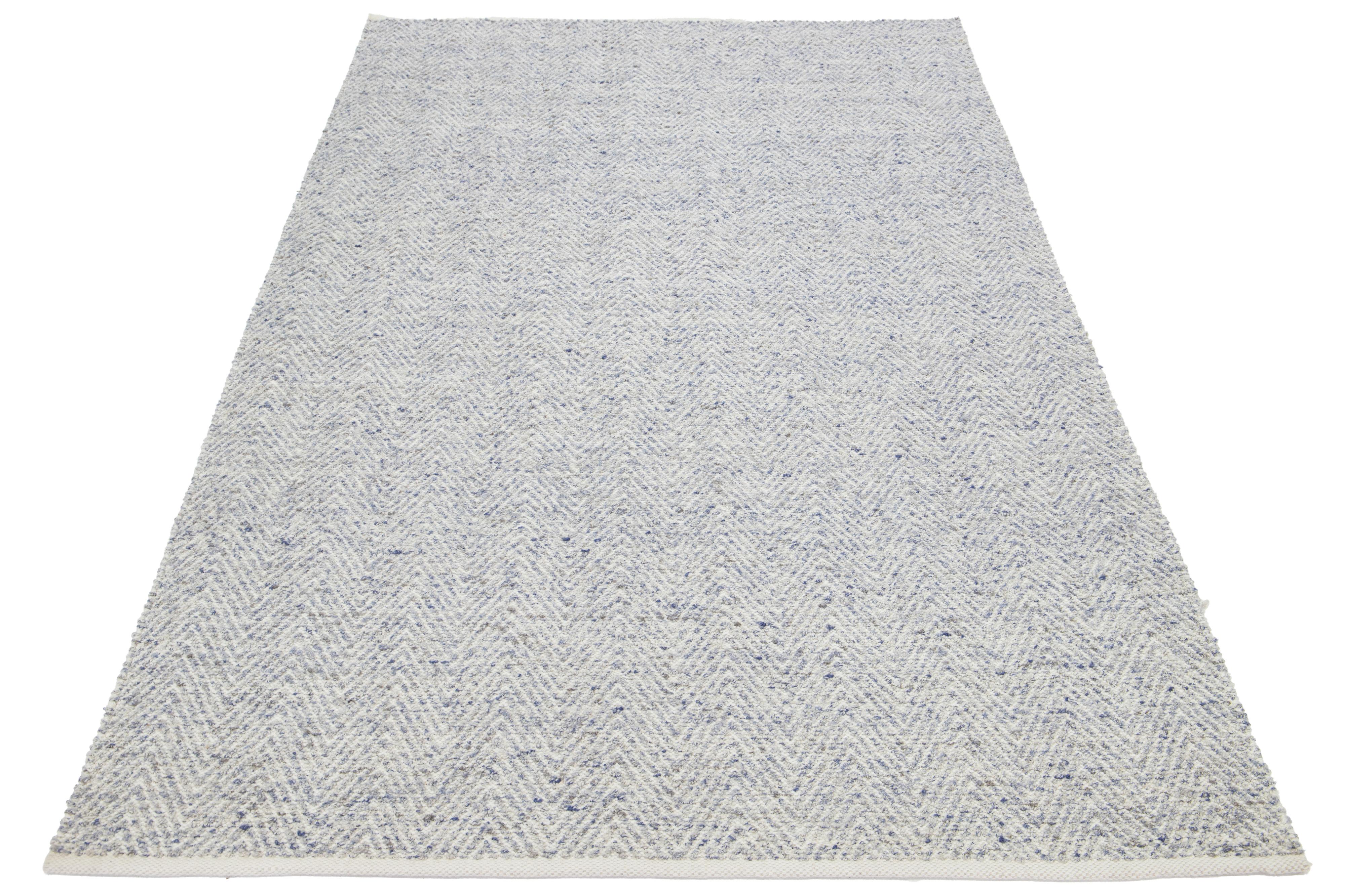 Questo bellissimo tappeto in lana lavorato a mano dalla texture moderna, che fa parte della nostra collezione Sasco, presenta un campo di colore avorio con accenti in blu e grigio. Il tappeto vanta anche uno splendido disegno strutturato che ricorda