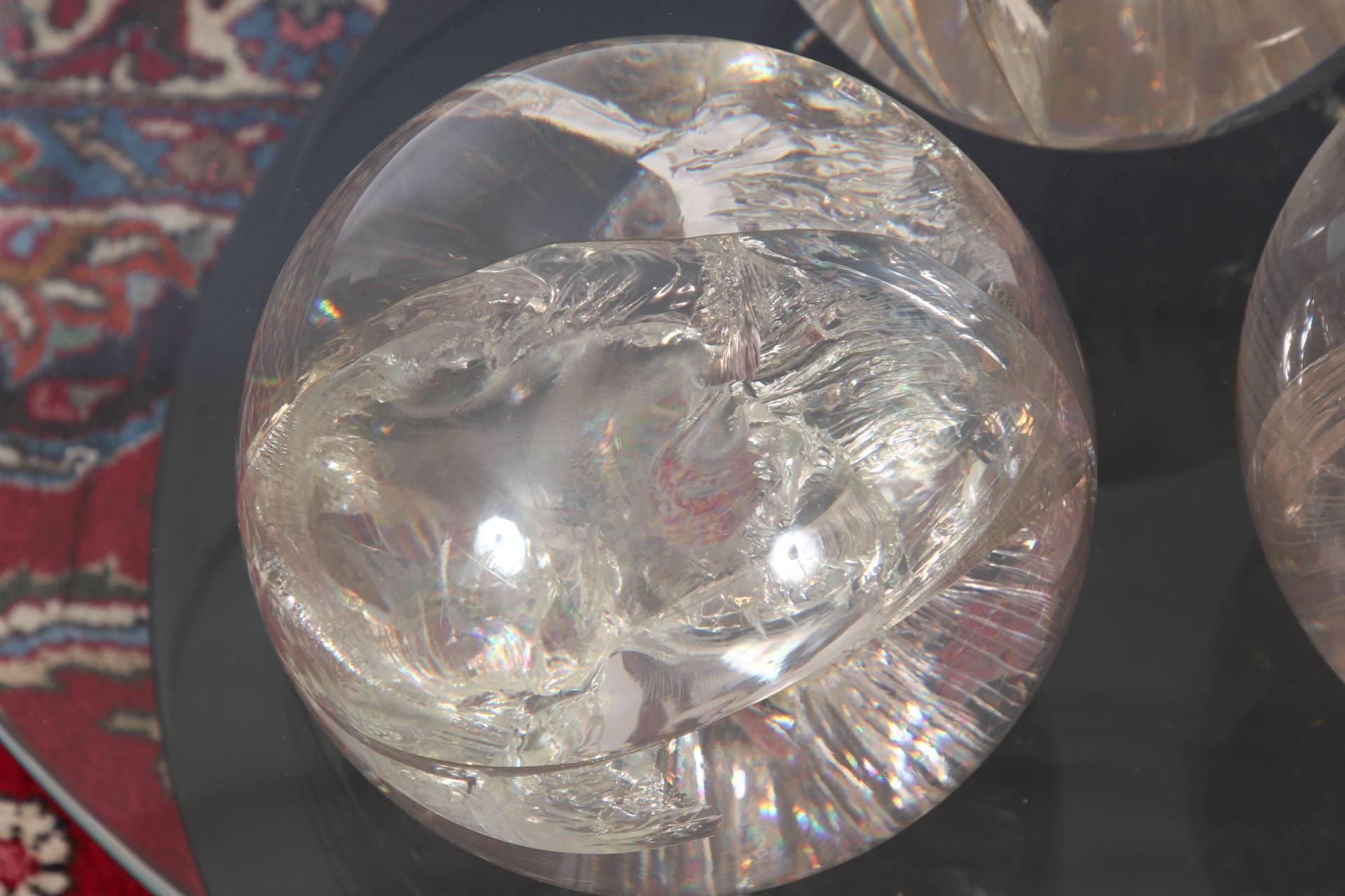 Three internally cracked Lucite spheres screw mounted on a round two-tiered back lacquer base. With a round glass top.
Condition: some scrapes to the base.