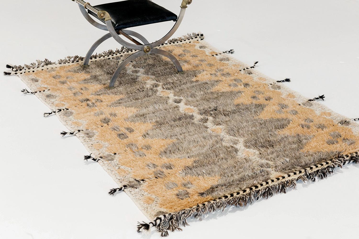 The 'Modlina' rug is a handwoven wool piece inspired by vintage Scandinavian design elements and recreated for the modern design world. The rug's shag balance and harmony, handwoven with a neutral flat-weave and unique piles of peach and natural