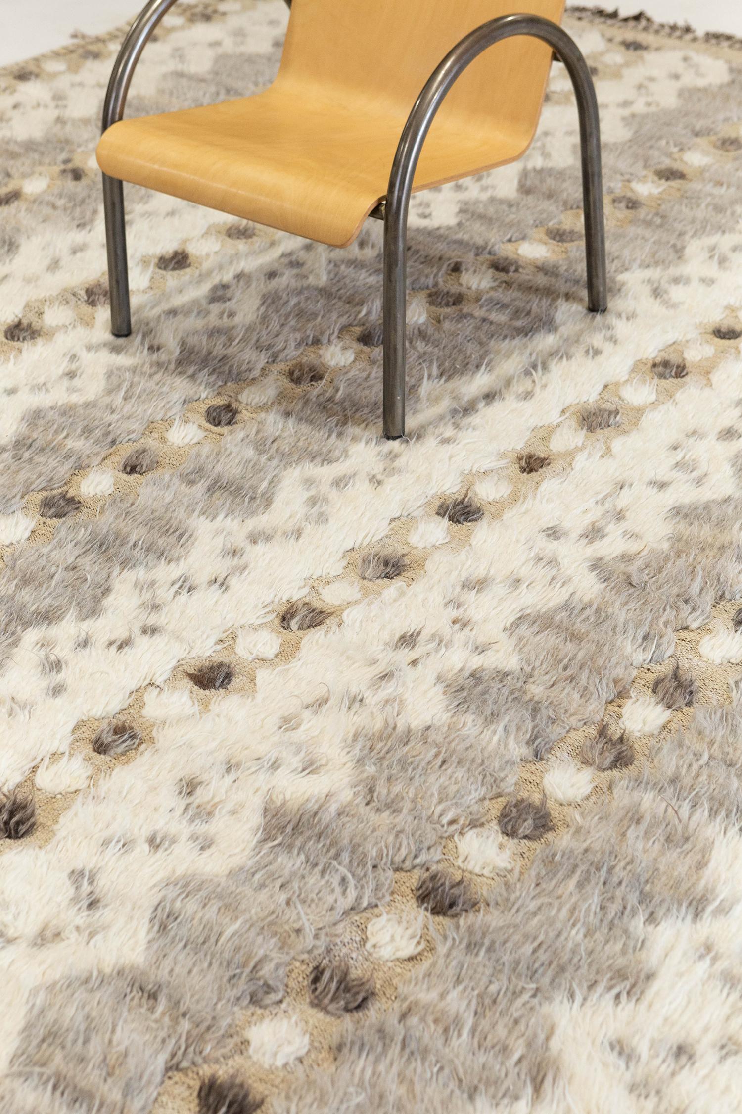 The 'Modlina' rug is a handwoven wool piece inspired by vintage Scandinavian design elements and recreated for the modern design world. The rug's shag balance and harmony, hand woven with a tan flat weave and piles of taupe and ivory. This