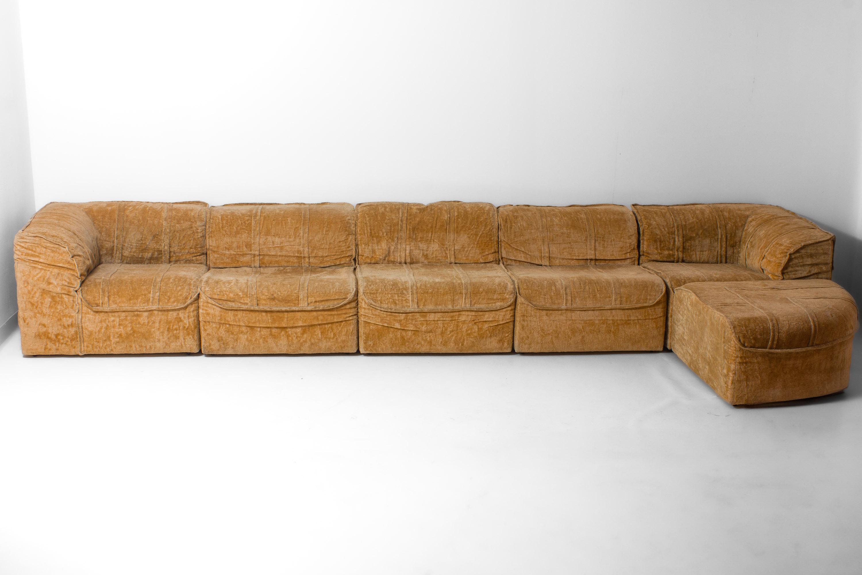 Seven-piece modular sofa made in Italy during the 1970s. The set includes 4 straight modules, two corner elements, and and a side piece, all upholstered in beige velvet fabric.

Each module has a low profile with rounded edges and vertical seam