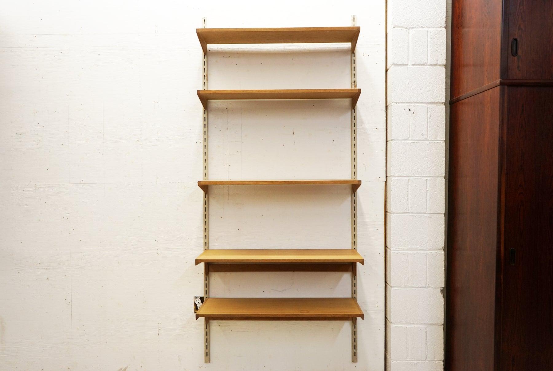 Oak single bank wall system by Kai Kristiansen, circa 1960's. 2 metal rails support cascading modular shelves with solid wood edges, measuring 2 x 12