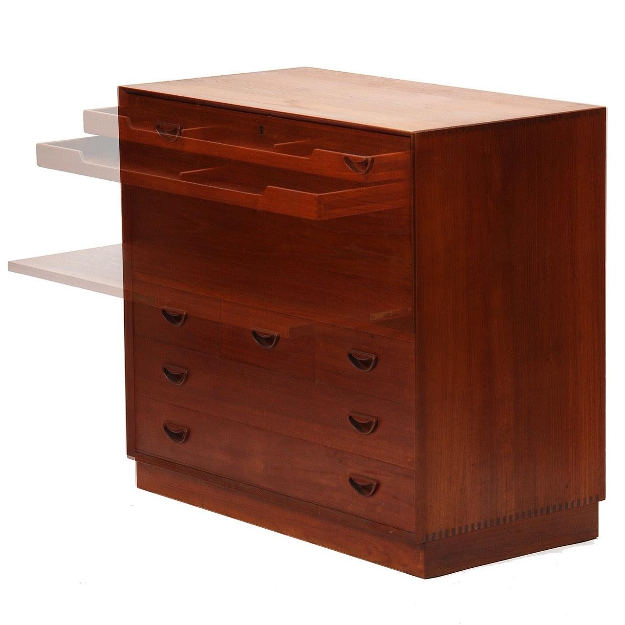 Un'elegante credenza o cassettiera modulare a cinque (5) cassetti in teak su una base a zoccolo con tiretti intagliati, incastri a coda di rondine a vista e un piano di lavoro a ribalta.