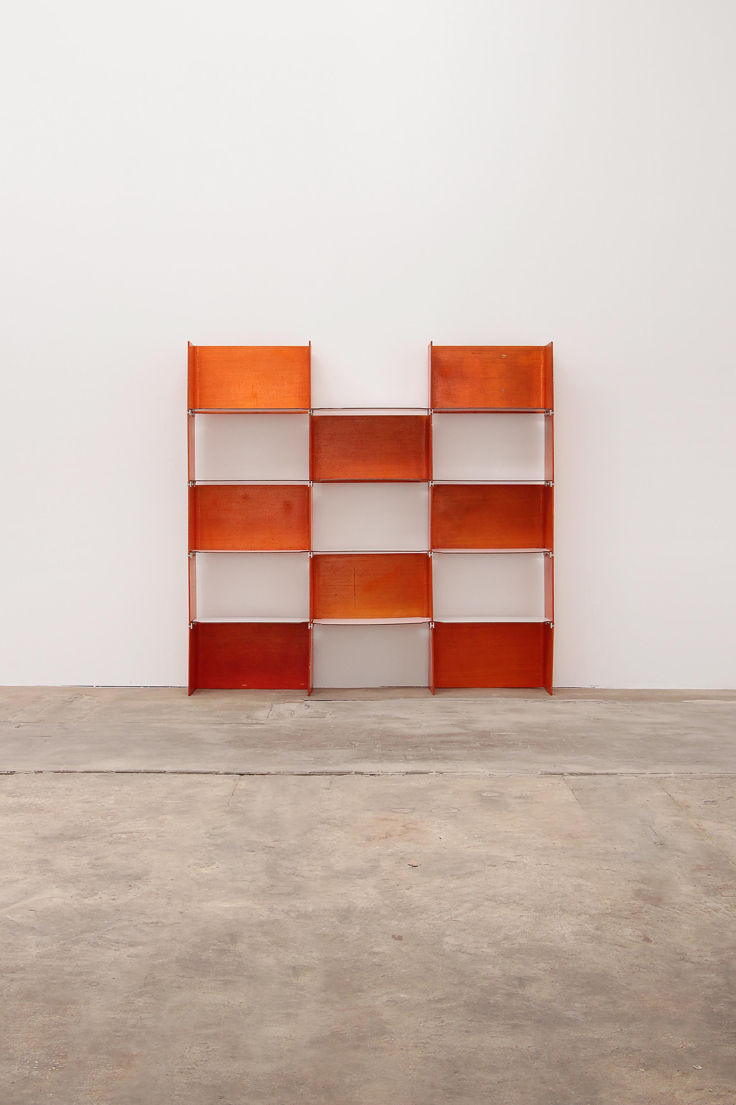 This is a French wall system orange in color and made of multiplex wood.

The freestanding flexible modular shelving system is built in plywood, reminiscent of the great French designer Jean Royere, France 1960. The system consists of connecting