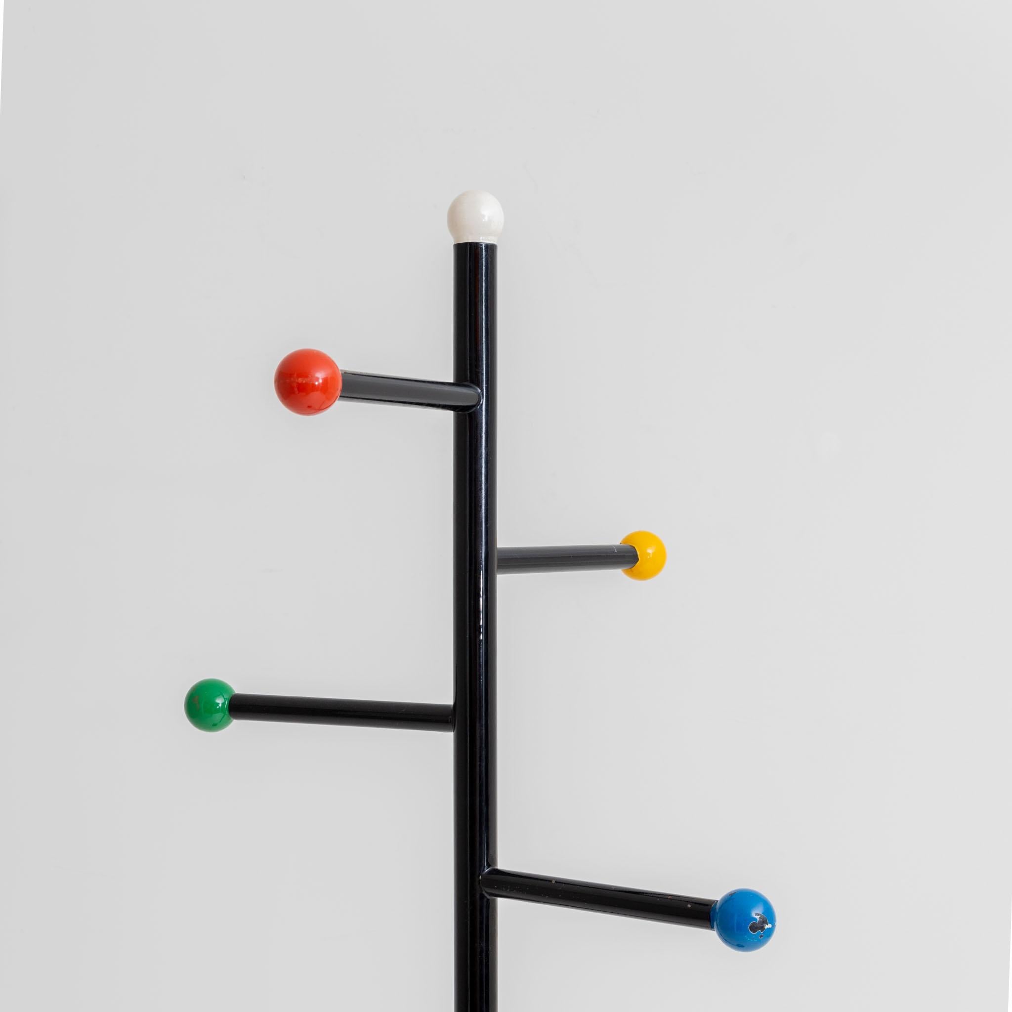 Metal coat rack with black base and colorful balls at the end of the clothes rails. Color worn off in places.
