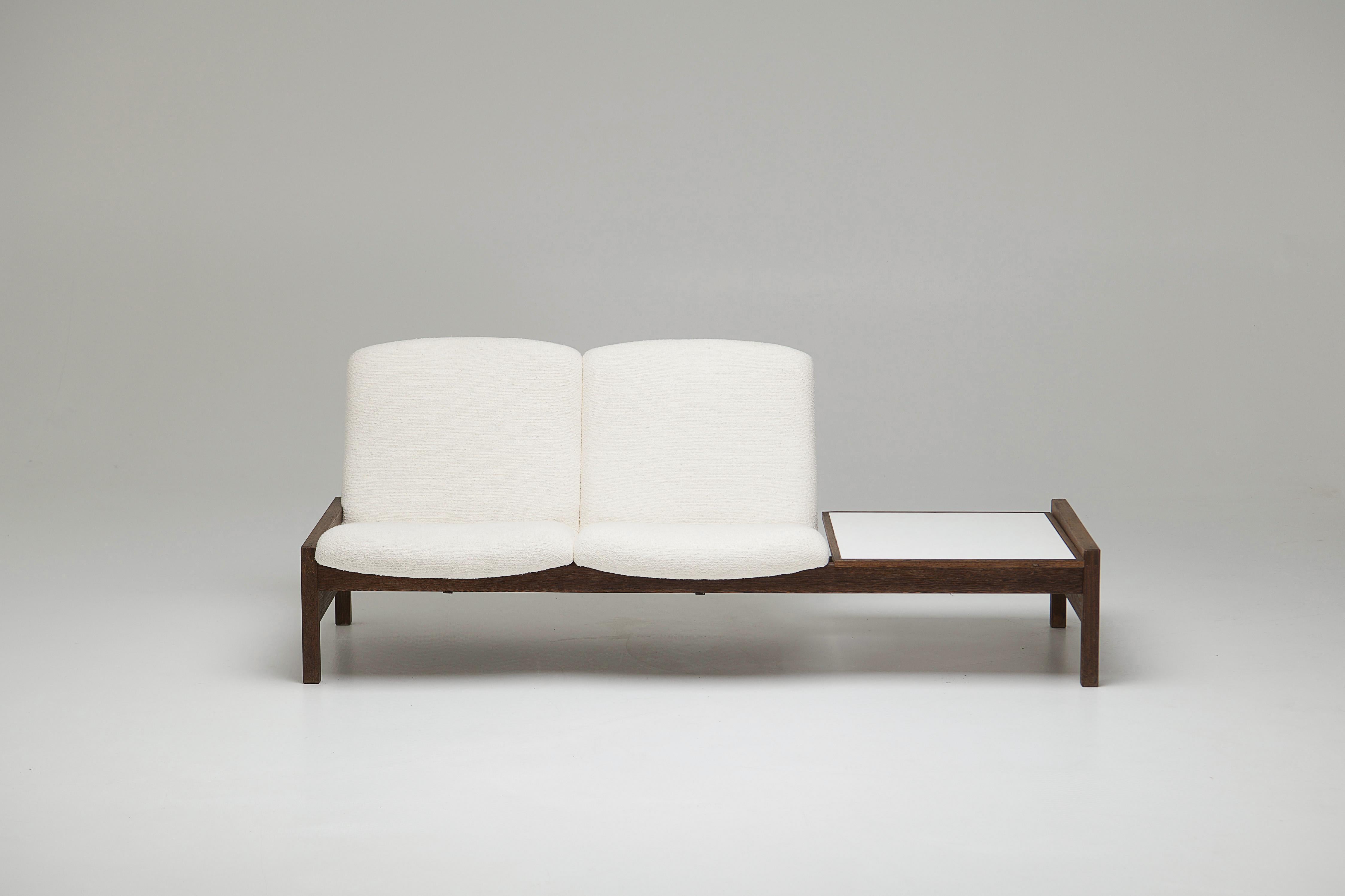 Un divano modulare minimalista con tavolino integrato e piano d'appoggio in laminato bianco. Progettata dal designer belga Georges Van Rijck per Beaufort negli anni Sessanta. 
 
Queste parti sono intercambiabili e permettono di trasformare il