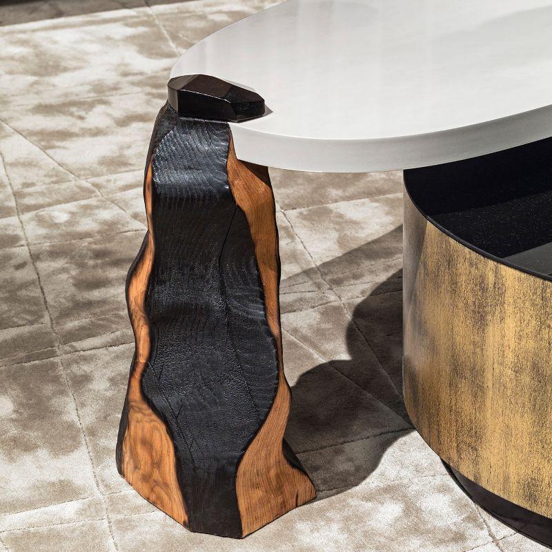 A sculptural and modular design of unparalleled sophistication, this set of two coffee tables features a lower piece enhanced with a gold leaf finish and a black mirrored glass top, and a higher element showcasing burnt oak legs and a mother of the