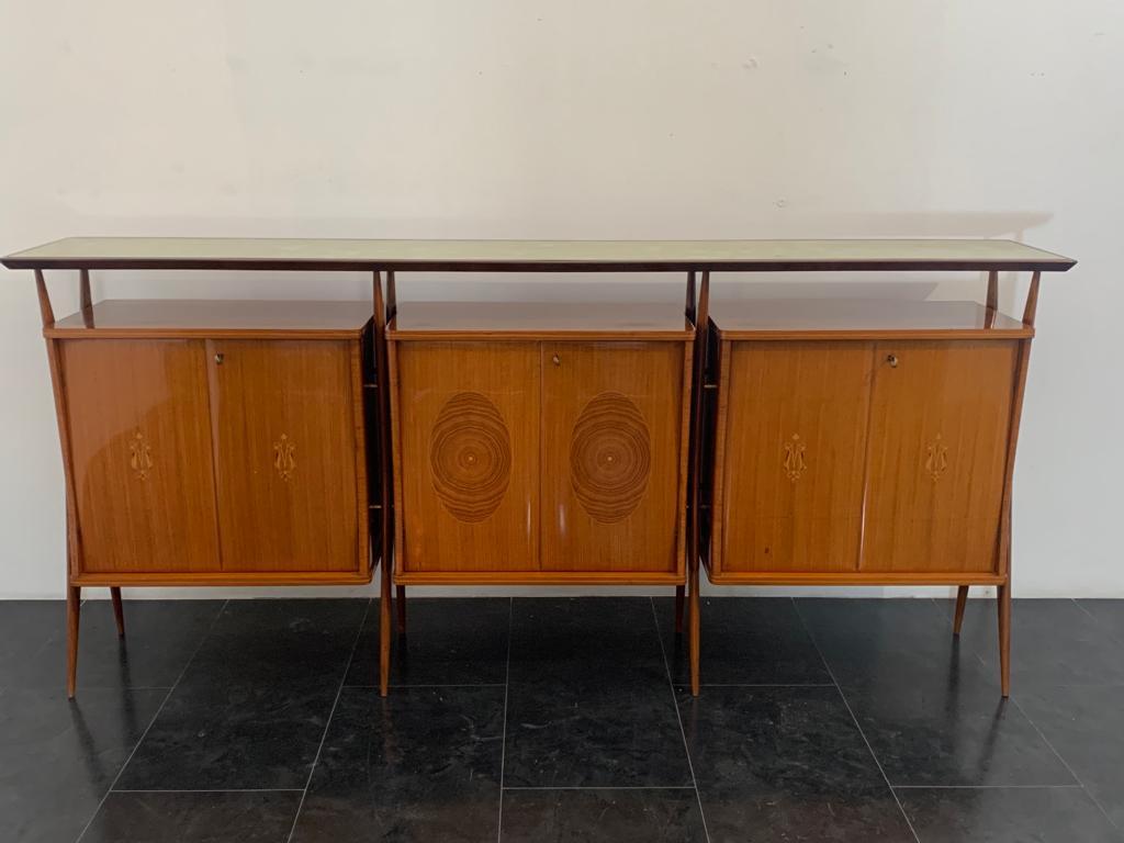 Modular sideboard attributed to Vittorio Dassi, 1950s. Rosewood structure, brass hardware, aqua green decorated glass top with solid rosewood frame. Each of the three modules has a pair of doors decorated with classical-style inlays; inside are aqua