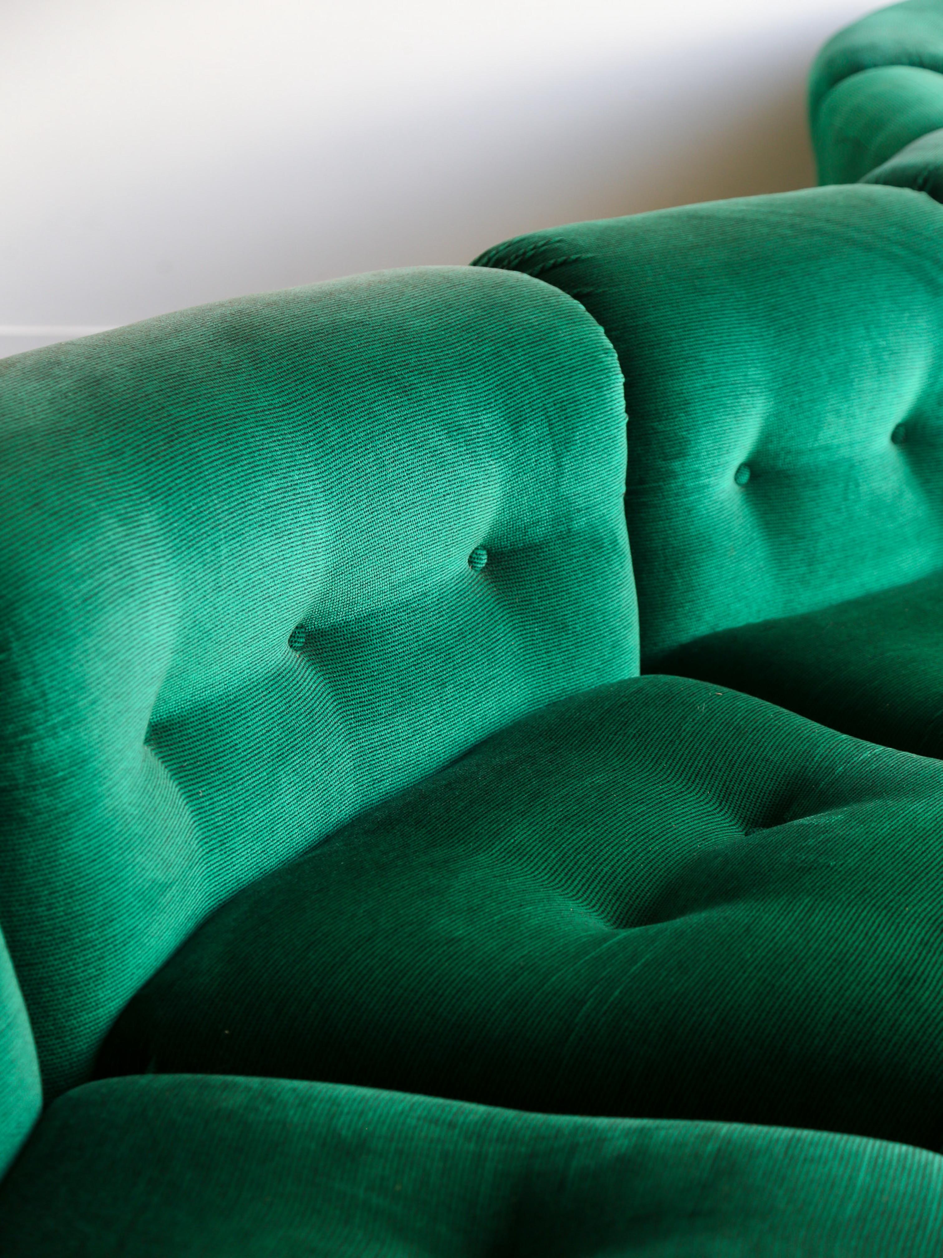 Il s'agit d'un meuble moderne du milieu du siècle revêtu d'un riche tissu de velours vert émeraude. La forme distinctive du canapé se caractérise par un design légèrement ondulé, idéal pour créer une déclaration dans les grands espaces de vie. Les