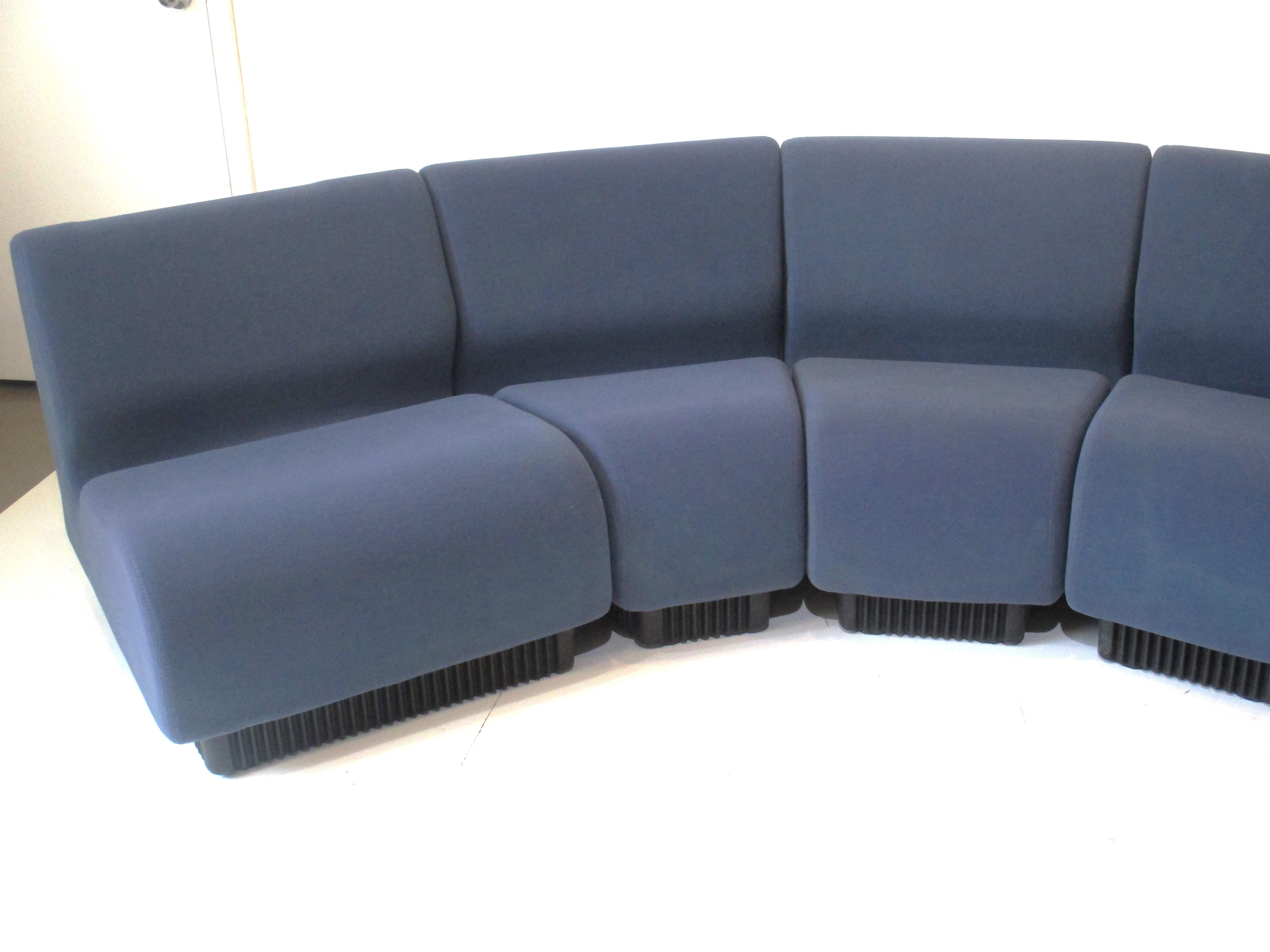 A six piece modular sofa set in a lighter cobalt blue with black ABS plastic kick bases. These pie shaped seating pieces are covered in a contract fabric that is soft and able to stretch a bit to conform to the shapes, the pieces can be set up in