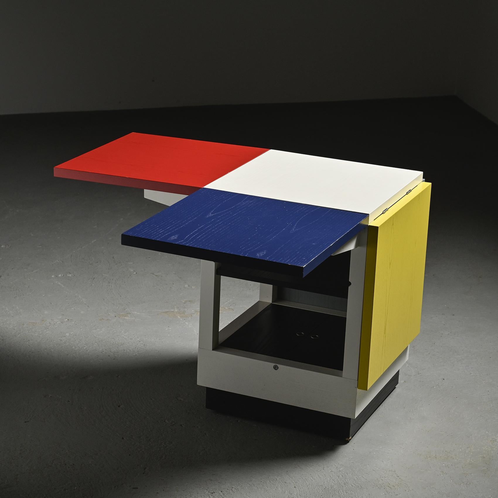  Coffee table model K10 N published by Tecta, Germany.

The cubic wooden structure, lacquered in white, supports four rotating tops painted in the primary colors red, blue, yellow and light grey, arranged around a central white square. This