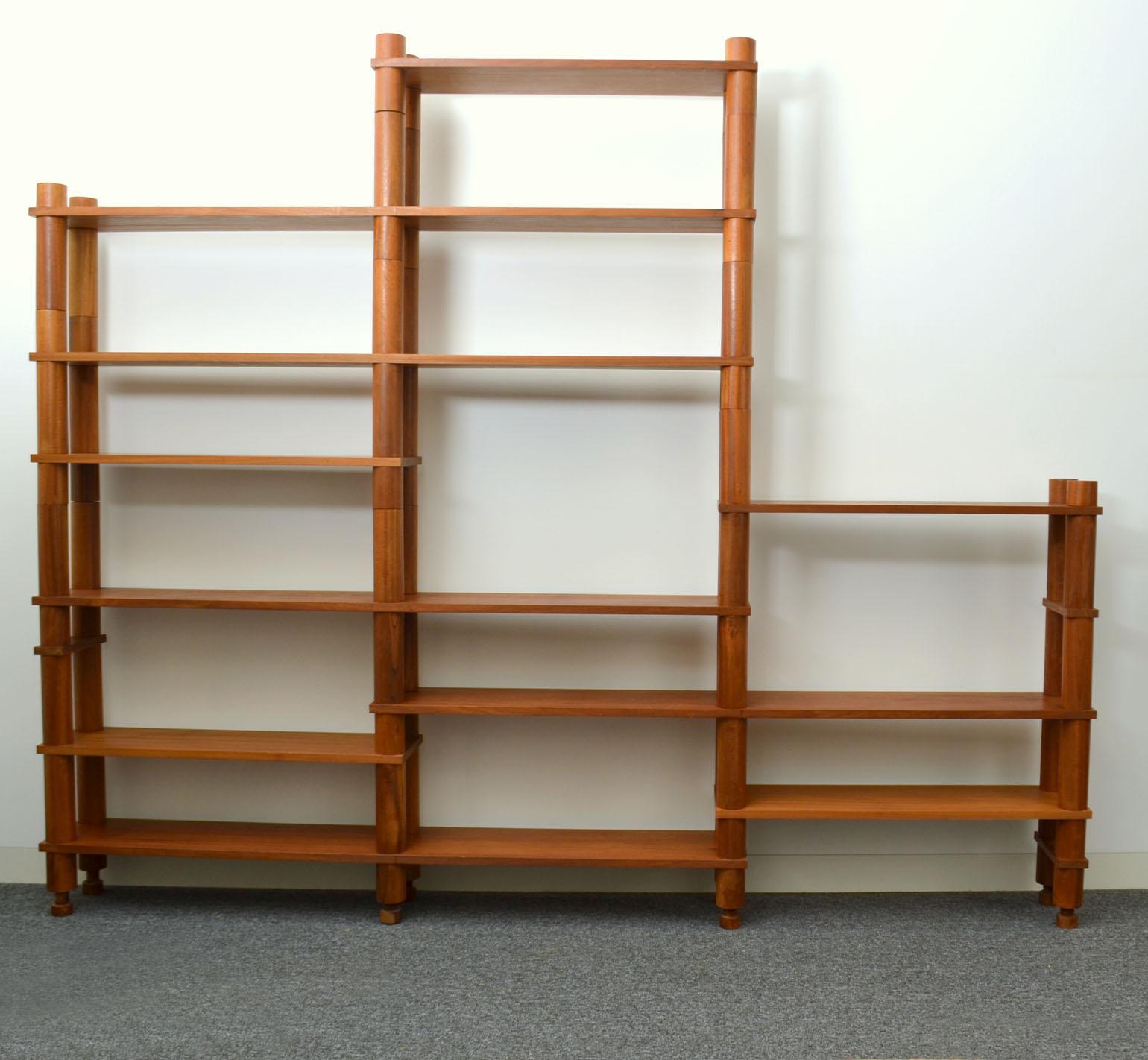 The free standing flexible modular shelving system was constructed in solid teak. The system is solely made from two sizes of cylindrical wooden uprights and connecting screw elements. The shelves large and small have four or six holes that are