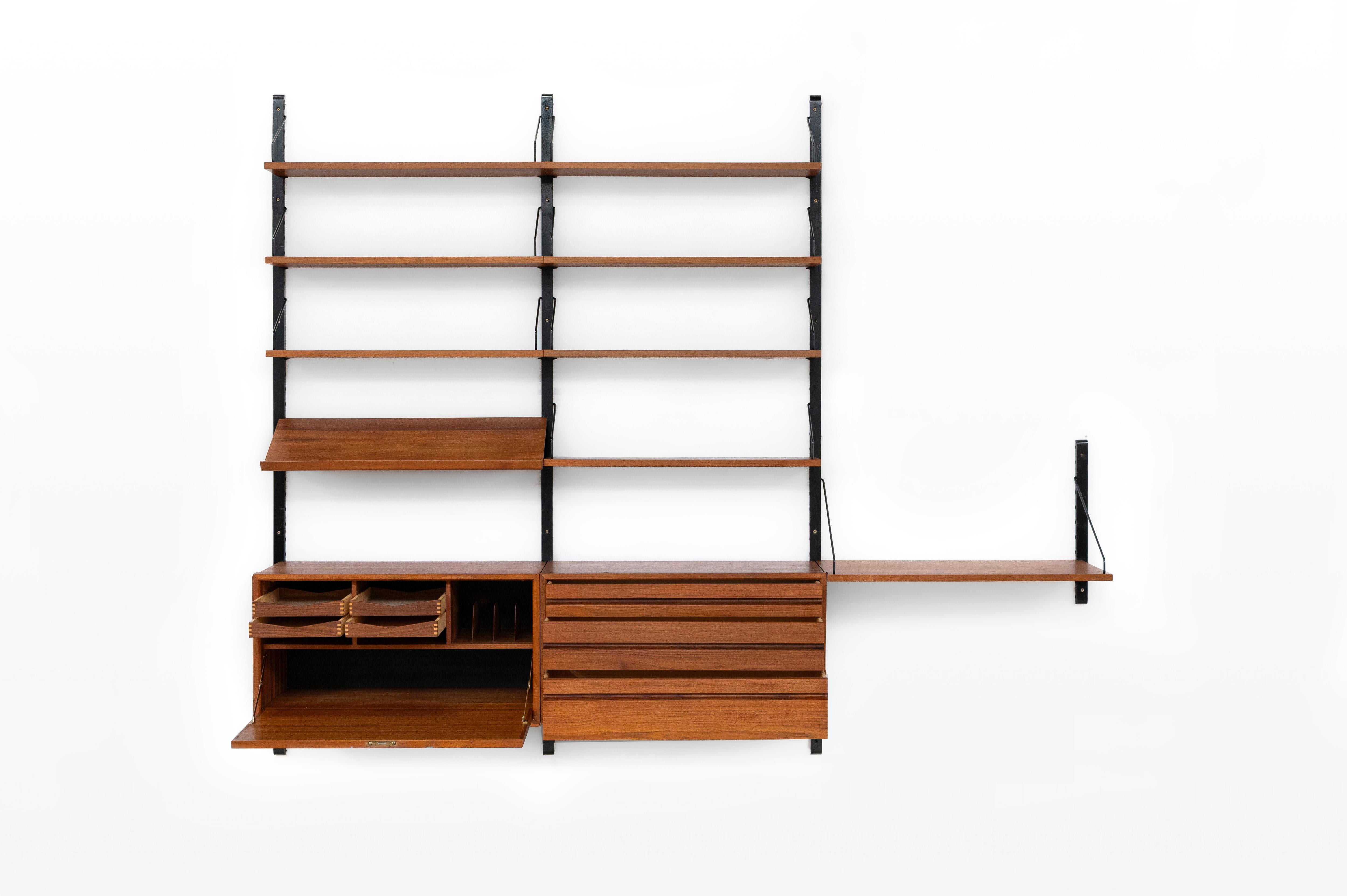 Danish modular wall unit by Poul Cadovius for Royal System. This teak setup has one drawer cabinet, one woven bar cabinet, one reading shelf, one desk shelf, four black wooden wall lats and seven bookshelves. Always adaptable and further