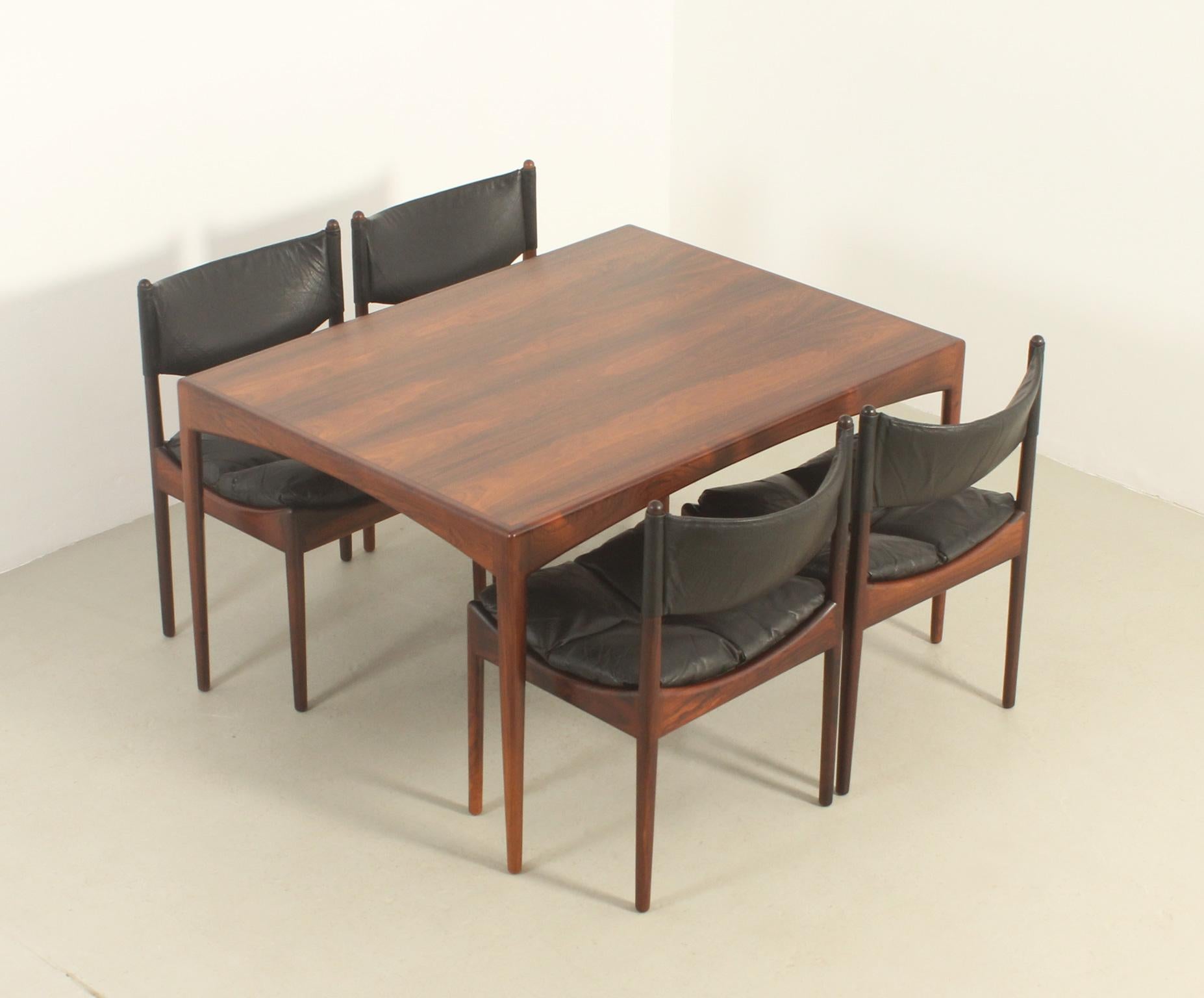 Modus dining set designed in 1961 by Kristian Vedel for Søren Willadsen, Denmark. Hardwood with stunning wood grain and original black leather upholstery. The set consists of a rectangular dining table and four side chairs. 