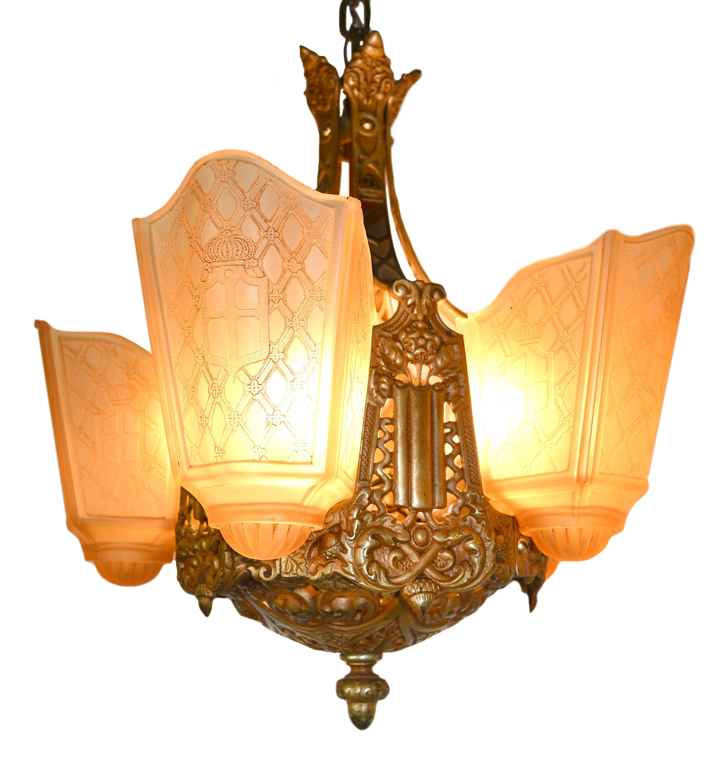 This finely crafted Moe Bridges chandelier features intricate detailing within the cast iron of the body and 5 stunning shades with a shield design. 

Brothers Henrik and Ole Moe founded the Moe Bridges Company in 1919 in Milwaukee, WI, where it