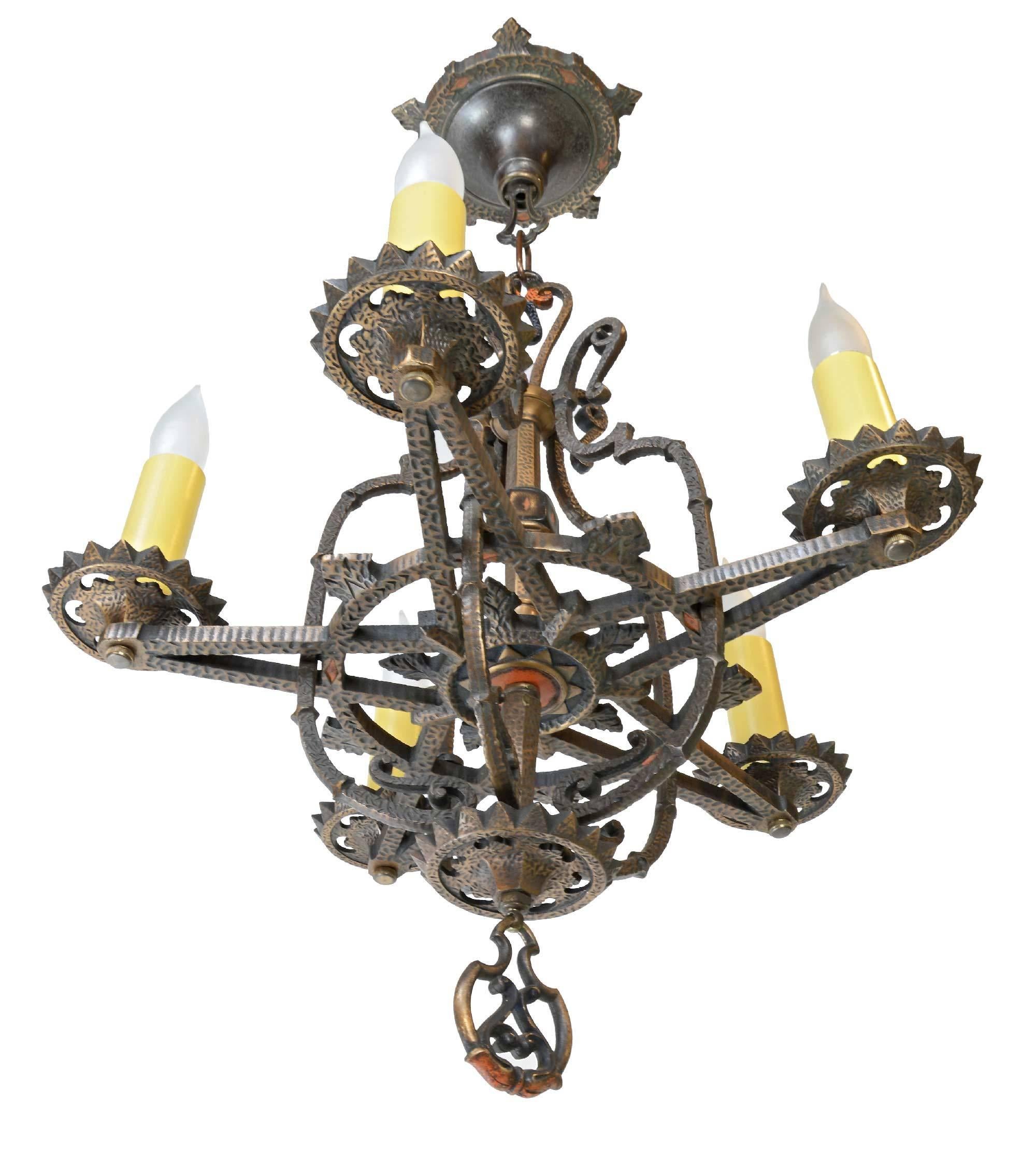 This hammered bronze chandelier by Moe Bridges features the original canopy, decorative finial, and five lights on arms radiating from the center in the shape of a star with a sunburst pattern on the bottom.

Brothers Henrik and Ole Moe founded the