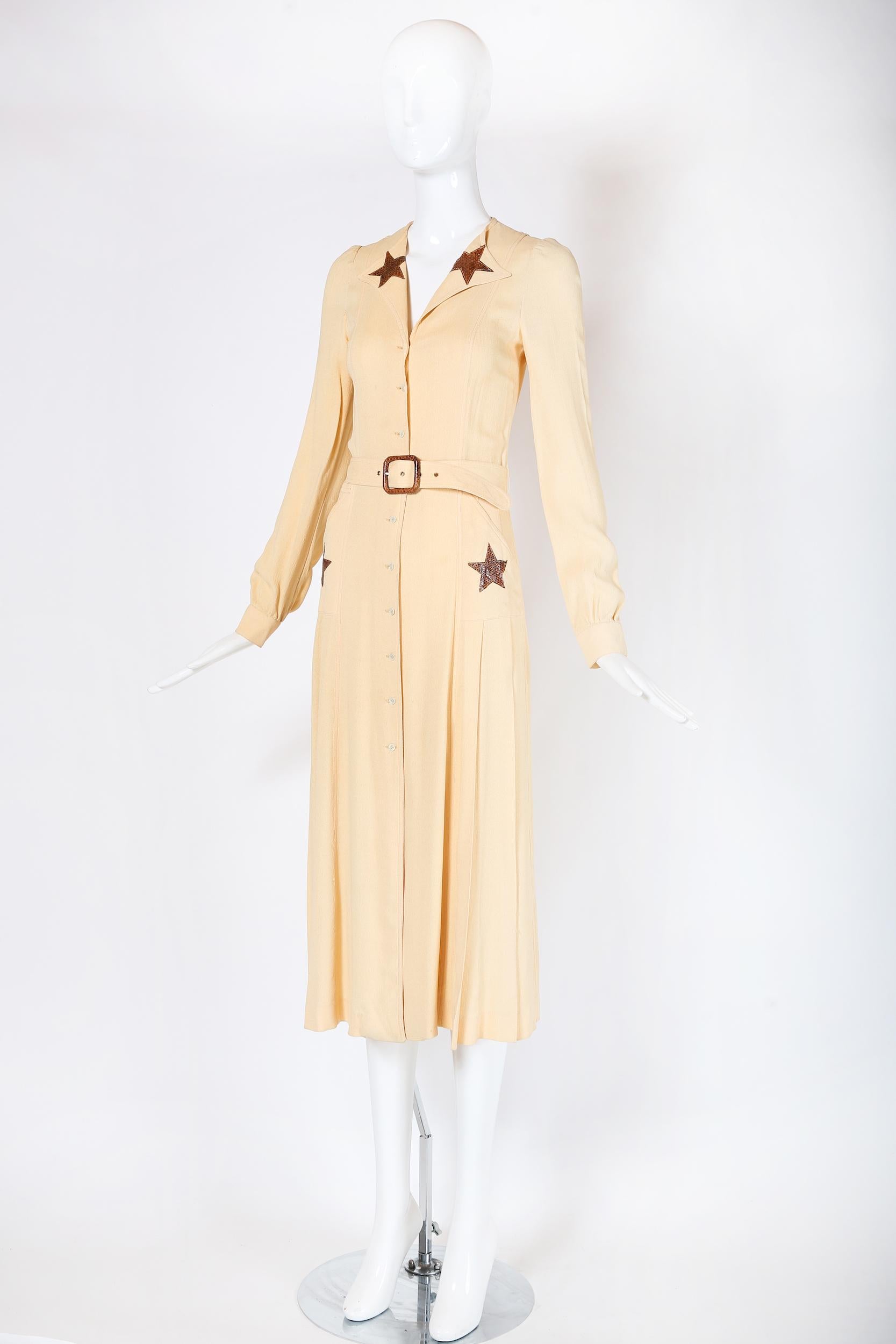 A 1970 pale yellow moss crepe fitted day dress by British designer, MOG that was purchased at Brown's, an upscale London department store. The dress has a box-pleated skirt, side pockets, small pearlescent buttons that fasten down center front, and