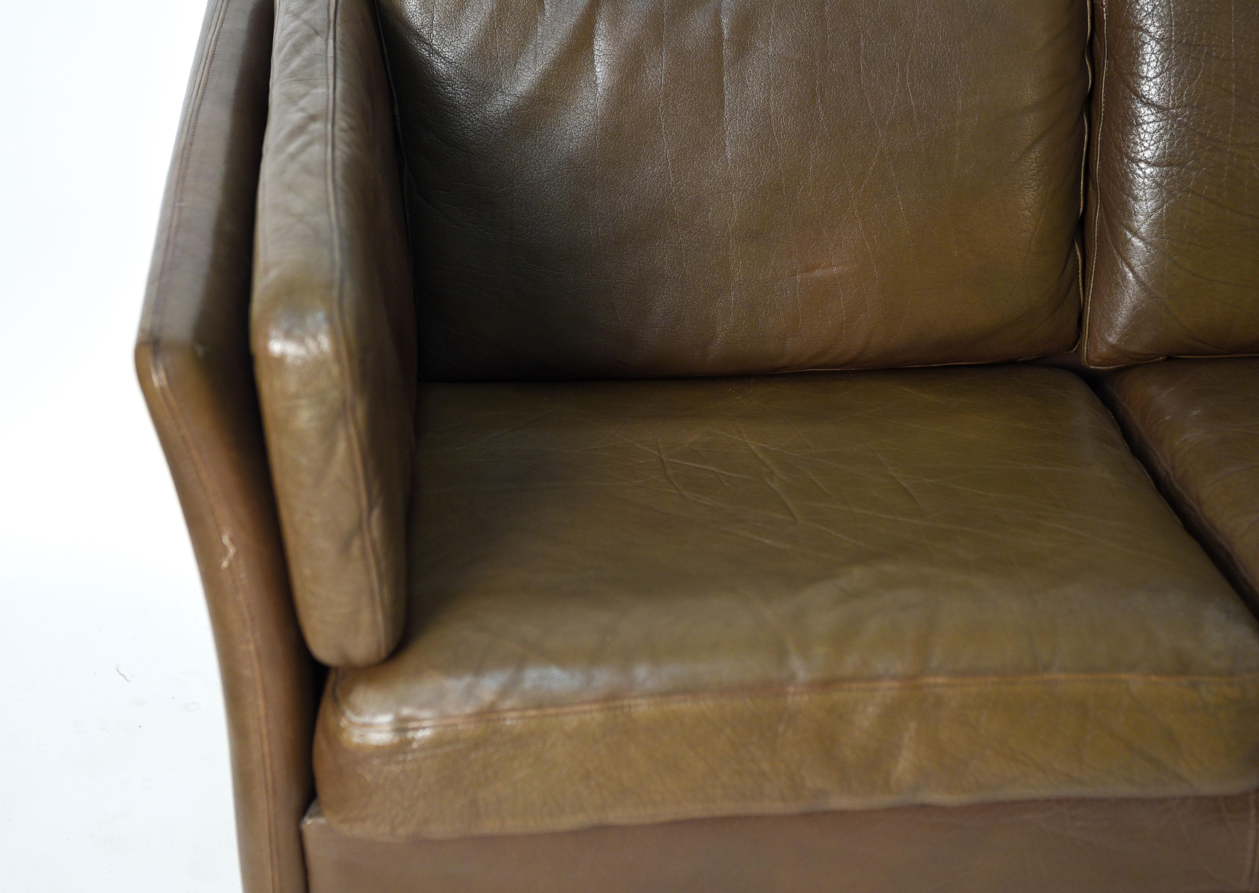 This Danish midcentury three-seat sofa is manufactured by Mogens Hansen, circa 1970s. In the manner of Danish designer Borge Mogensen. This sofa is upholstered in buffalo hide that has an attractive patination consistent with age and use.