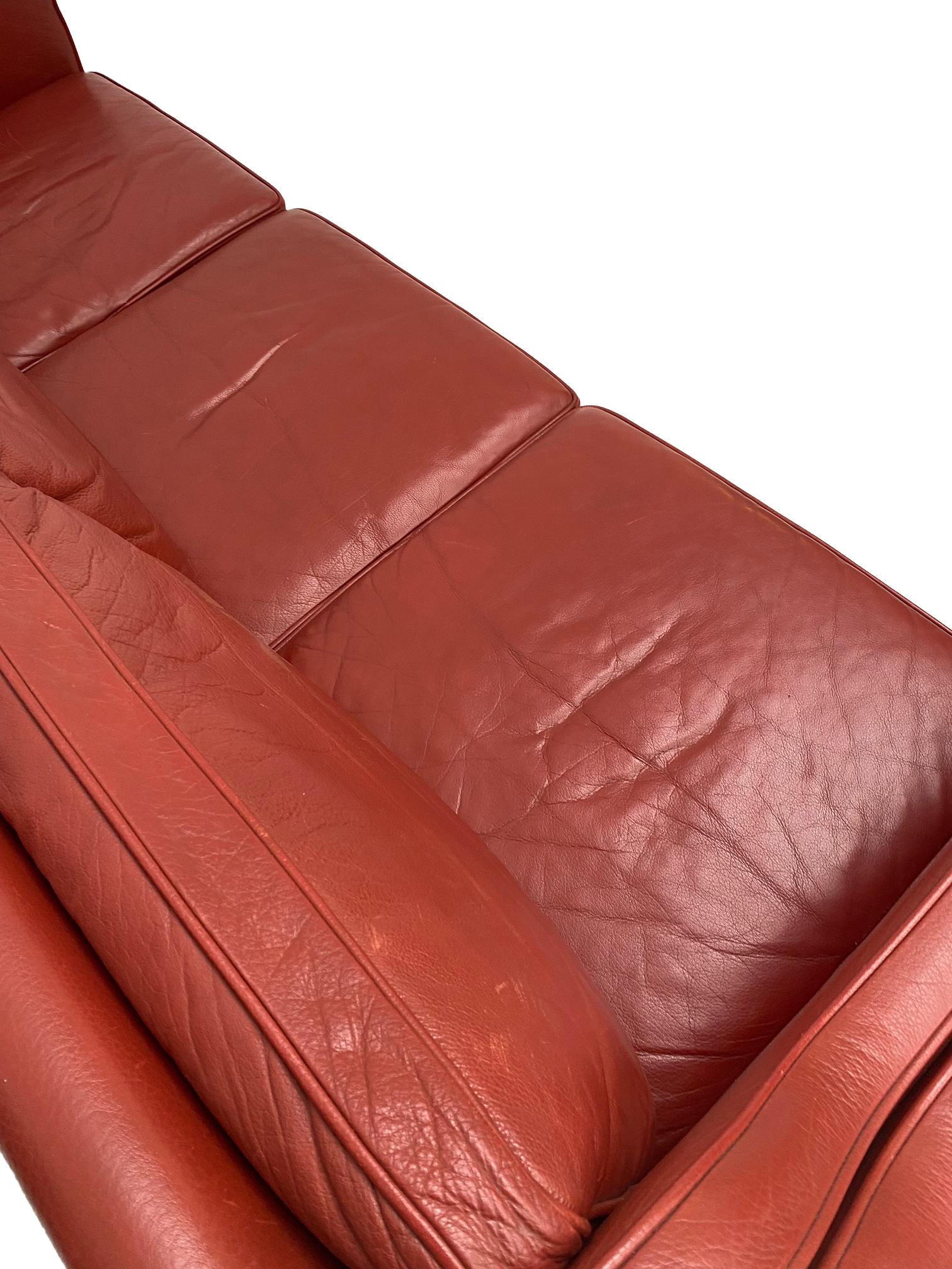 A classic yet striking design, this red leather 3 seater sofa by Mogens Hansen would make a wonderful addition to any home or work environment. 

In a charming Postbox red colour, this sofa would make a prominent feature for any space. The sloped