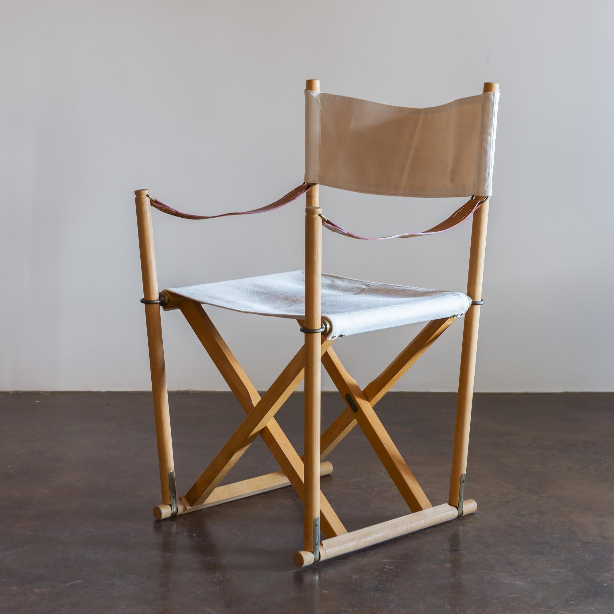 Set of six beech and canvas folding chairs with storage stand, by Mogens Koch for Rud Rasmussen, Denmark. Natural linen canvas sling seats and backs with full-grain leather straps and brass fittings.