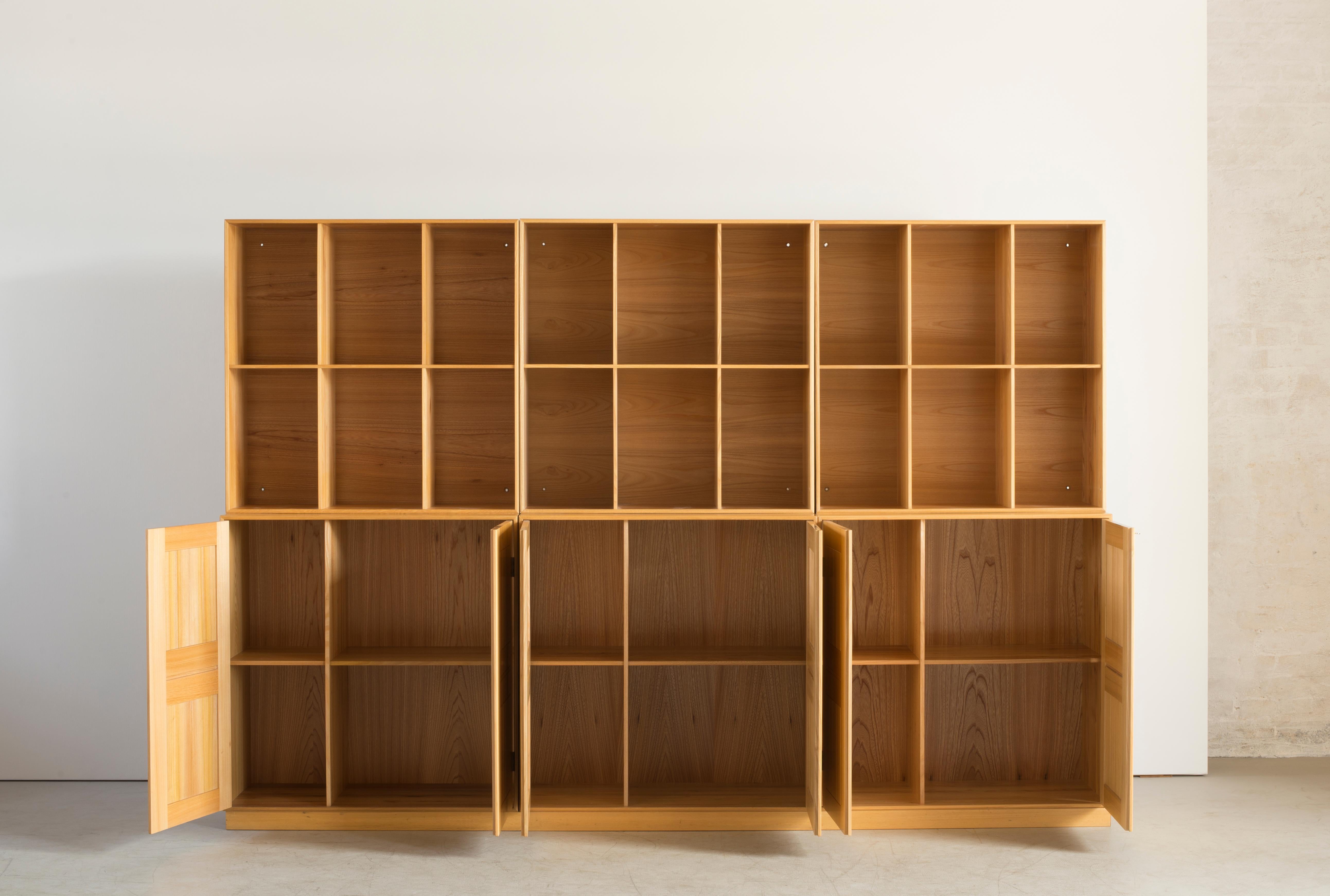 Mogens Koch Elm wall unit consisting of three cabinets with three matching plinths and three bookcases. Executed by Rud. Rasmussen, Copenhagen.

Reverse with paper labels ‘Rud. Rasmussen/ Snedkerier / København / Denmark.