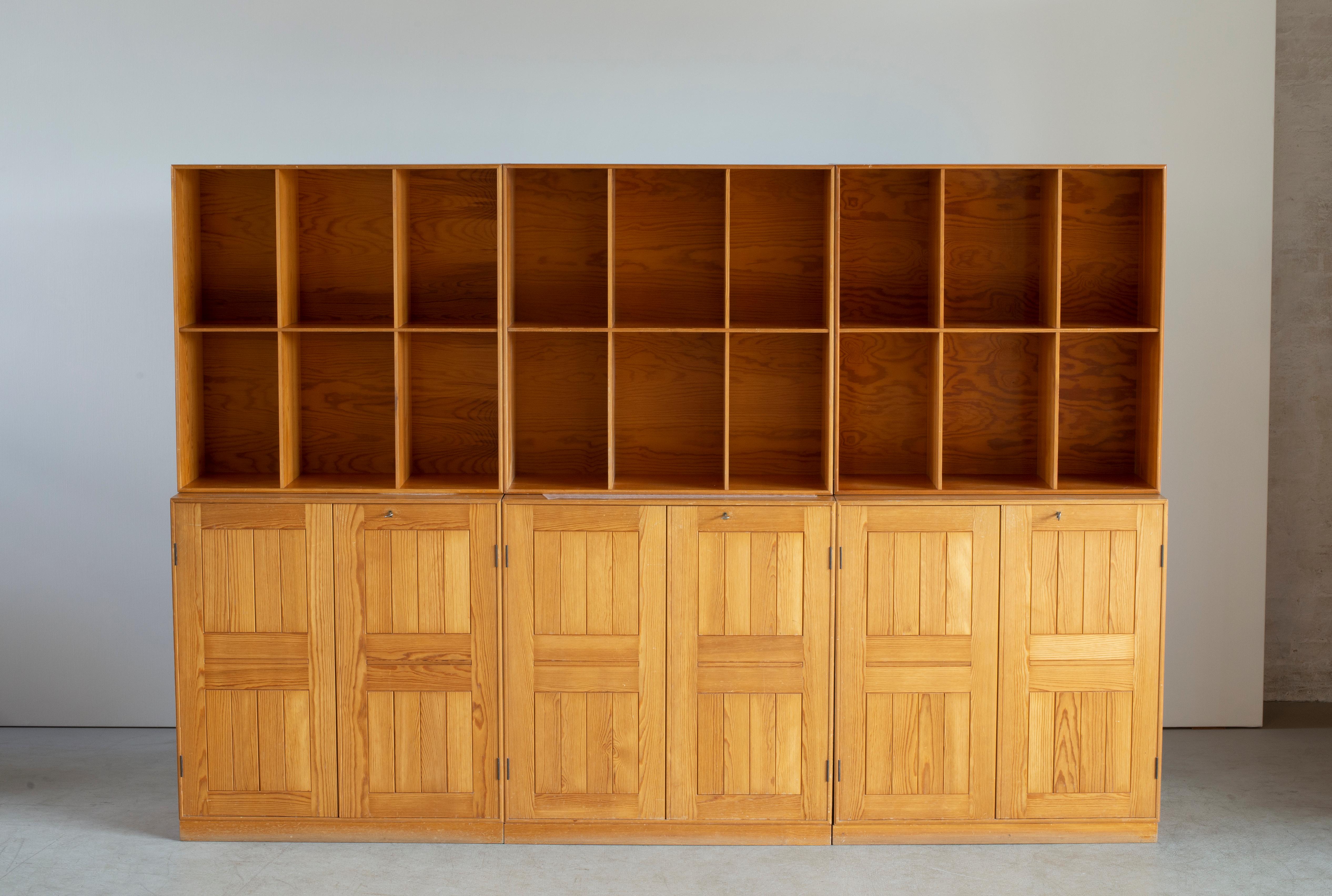 Mogens Koch pine wall unit consisting of three cabinets with three matching plinths and three bookcases. Executed by Rud. Rasmussen, Copenhagen.

Reverse with paper labels ‘Rud. Rasmussen/ Snedkerier / København / Denmark.