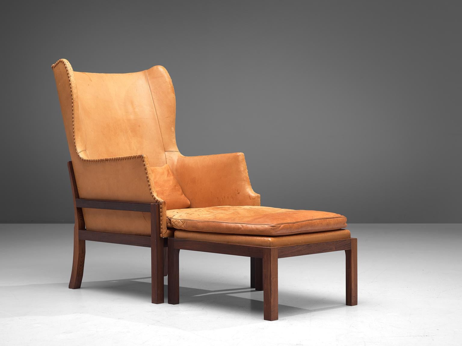 Mogens Koch for Rud Rasmussen, wingback chair and ottoman model MK50, mahogany and leather, Denmark, design 1936, manufactured 1964-1979.

Mogens Koch's wingback chair is inspired by Kaare Klint's furniture design, which in turn is inspired by