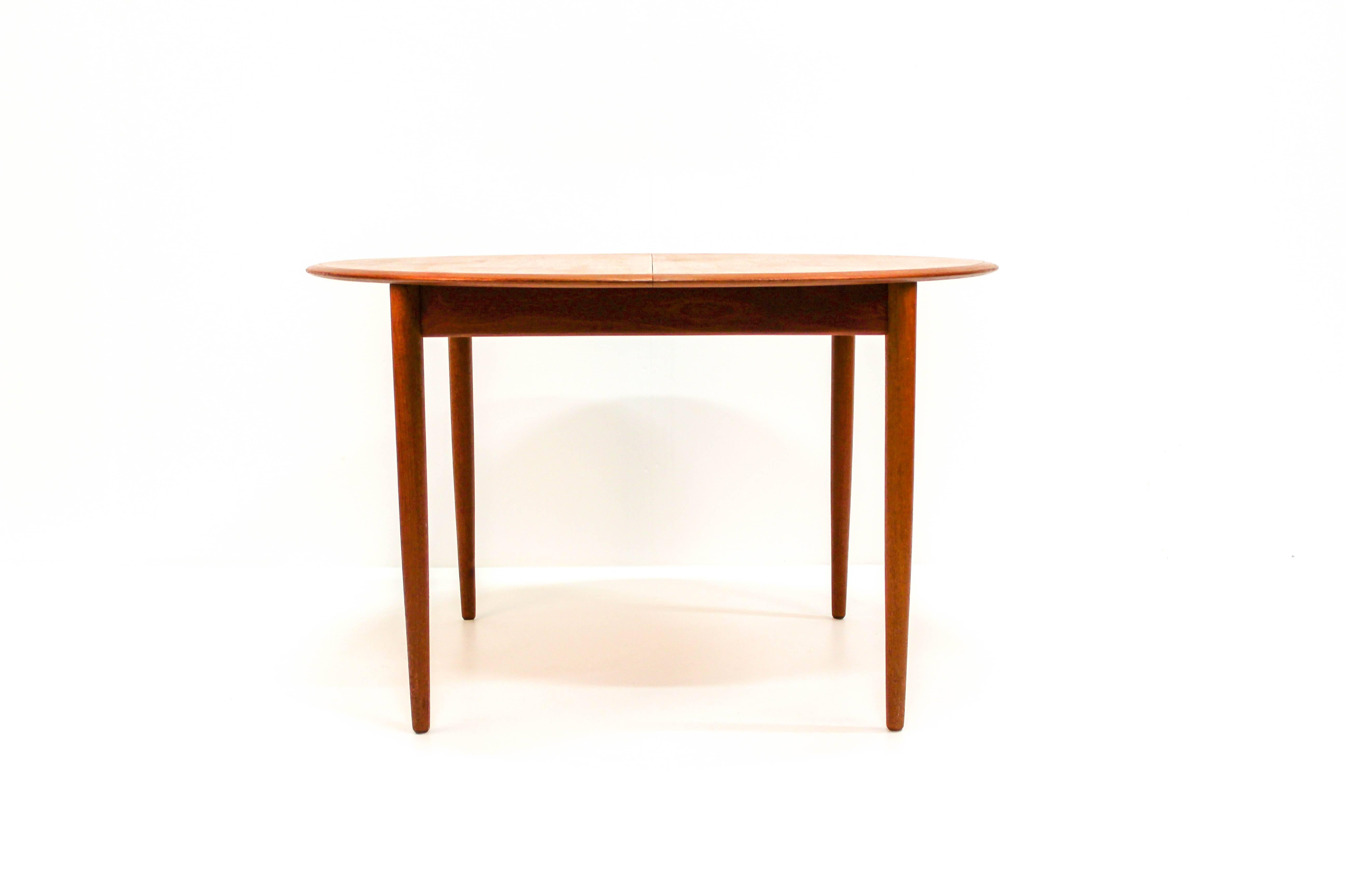 Midcentury Danish dining table designed by Arne Hovmand-Olsen and produced by Mogens Kold. The table has a built-in fold-up leaf and nice details such as tapered solid teak legs. 

The table is in very good vintage condition with minor signs of