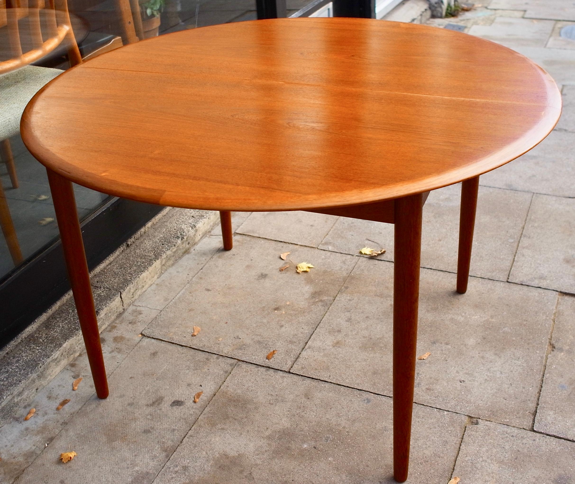 1960s round teak Danish dining table with fold out extension, allowing it to seat 6 place settings and perhaps up to 8. This beautiful example of a quality dining table was designed by Arne Hovmand-Olsen and produced by Mogens Kold. The table has