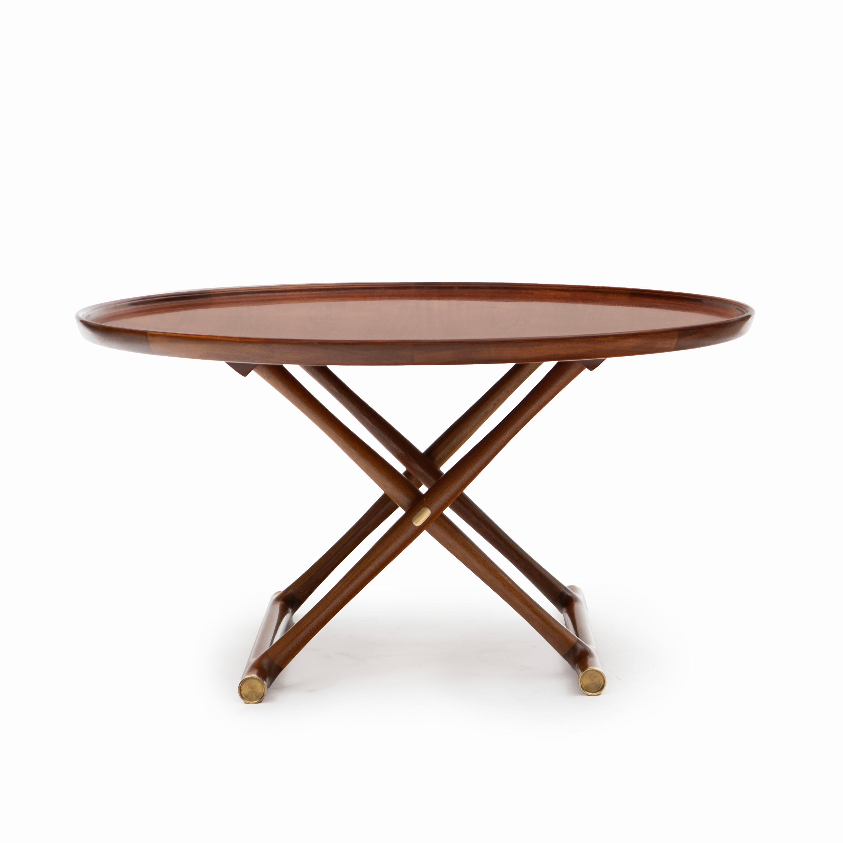 Mogens Lassen, Danish 1901-1987

Circular mahogany “Egyptian” folding occasional coffee table for A.J. Iversen, designed in 1935.
Foldable frame, top with raised edge and unusually beautiful grain. Beautiful details on feet in the form of brass end