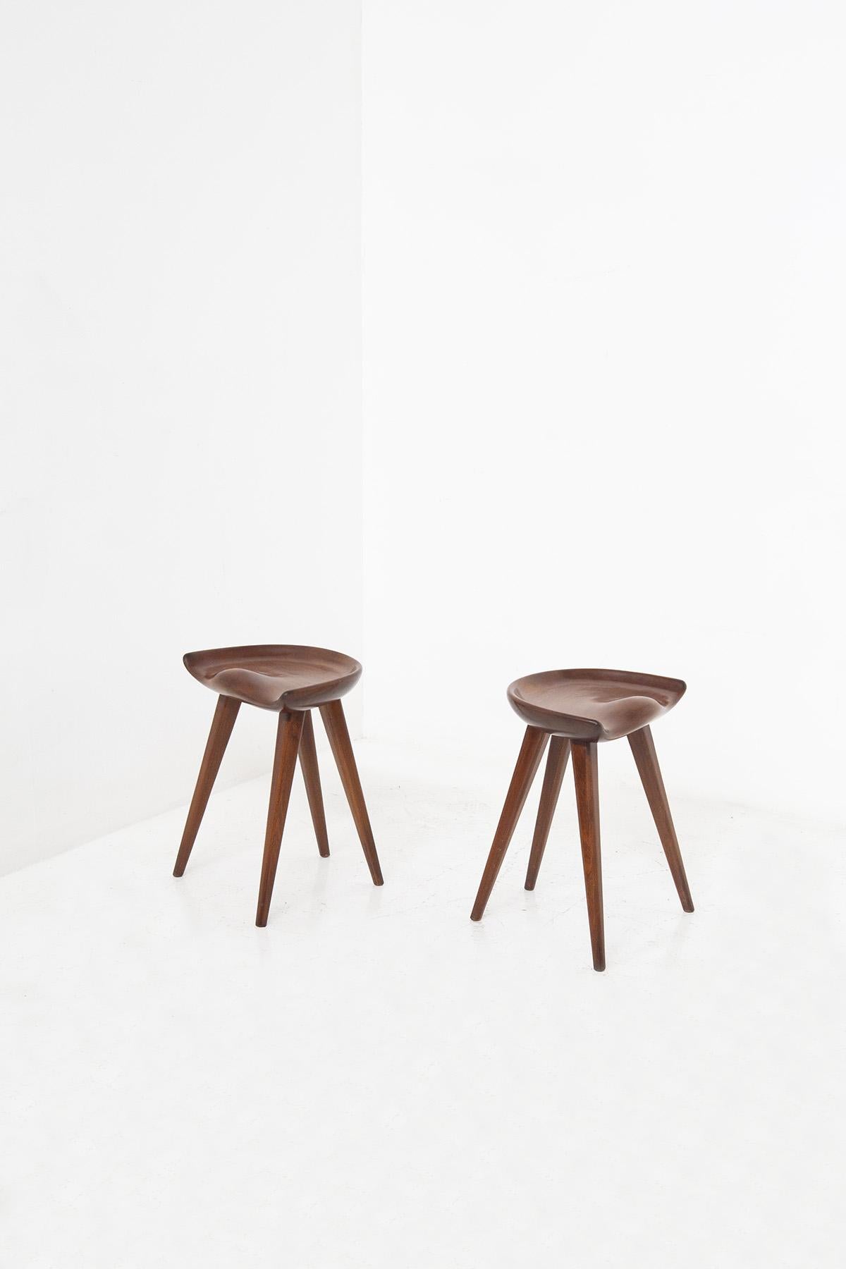 Sculptural pair of Danish-designed stools, designed by 1960s designer Mogens Lassen. The stools have a beautiful sculptural and iconic line. Its very fluid and harmonious lines denote great woodwork. Its finely carved seat has a very cosy shape in