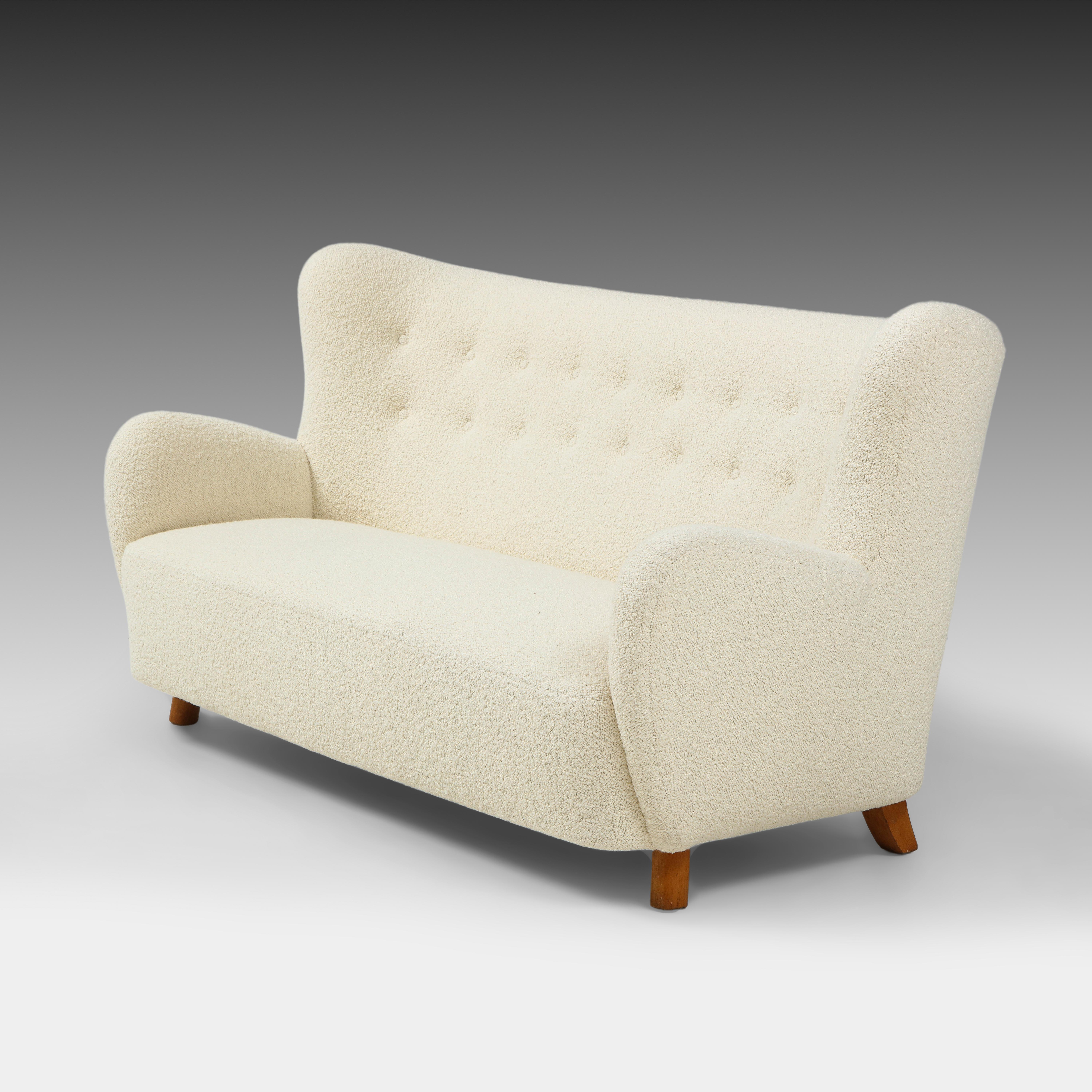 Mogens Lassen seltenes schönes Modern Scandinavian Sofa in elfenbeinfarbenem Bouclé mit leicht geschwungener und getufteter Rückenlehne und geschwungenen Armlehnen auf gebeizten Buchenholzbeinen. Dieses ikonische dänische Sofa der Moderne aus den