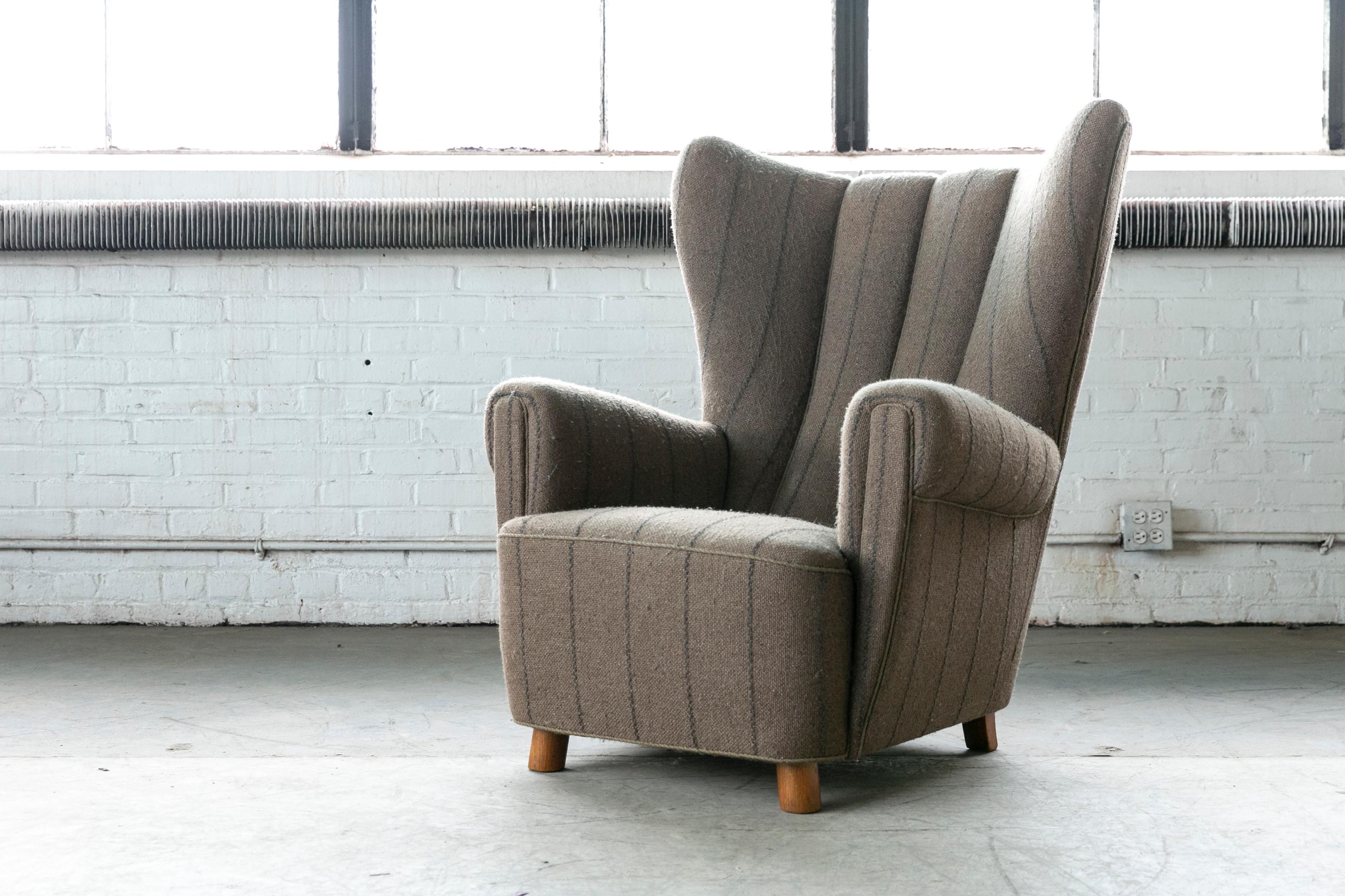 Super charming 1940s high back lounge chair in the style of Mogens Lassen with very sculptural organic shape and harmonious proportions. Slightly splayed front legs typical of Lassen designs. Raised on stained beech legs and beech frame with coil