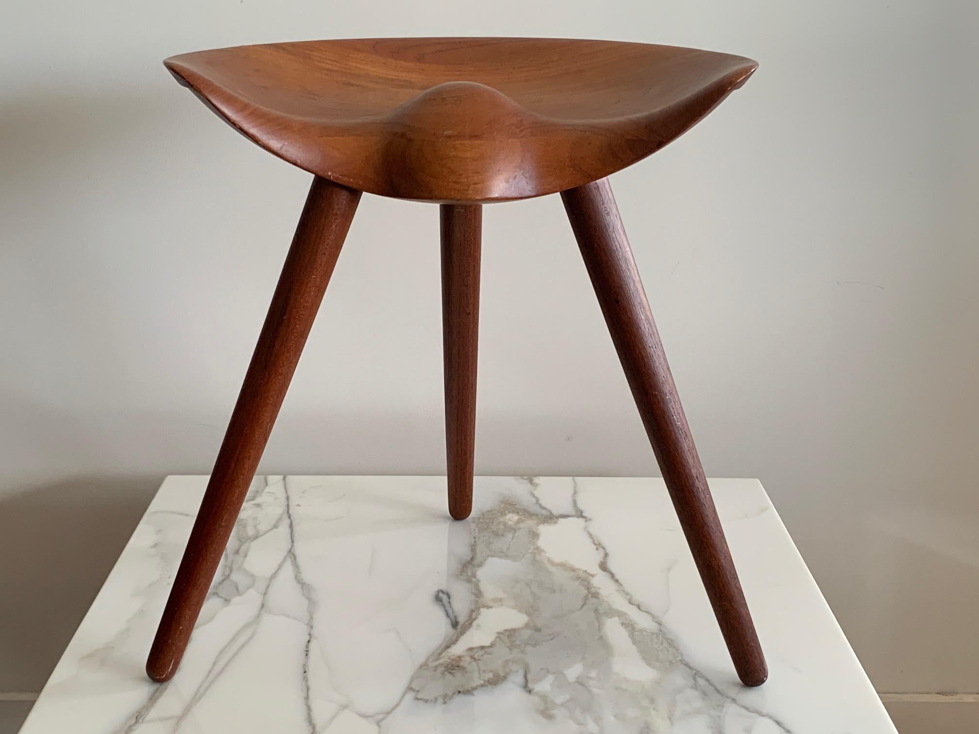 A classic vintage and original Mogens Lassen three legged stool in teak. Beautiful patina, great sculptural form.