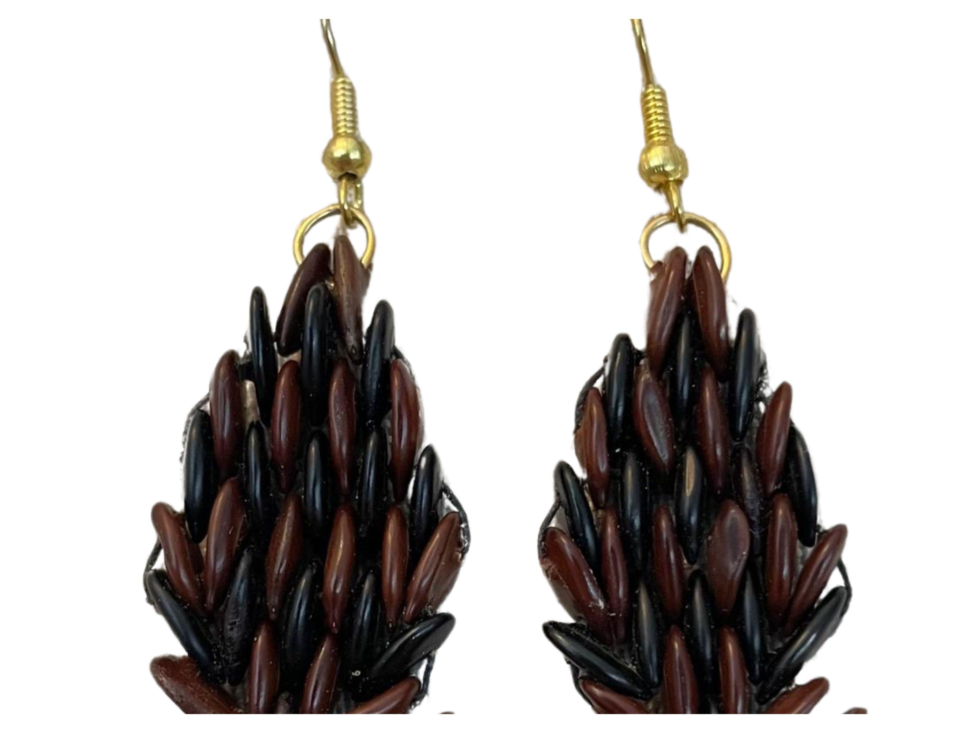 Ti presentiamo l'orecchino a fiamma Botanique Mohagany, un capolavoro di artigianato tradizionale meticolosamente realizzato a mano con semi di tamarindo selvatico. Questo orecchino, realizzato a mano, mette in risalto i toni caldi e ricchi del