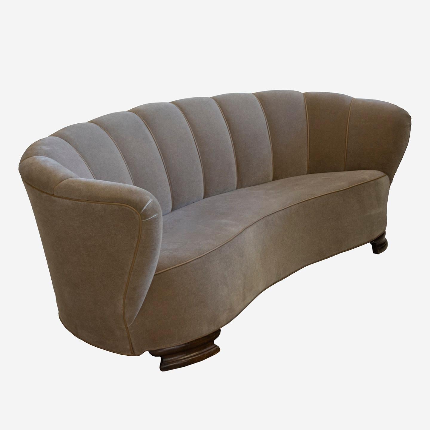 This outstanding Art Deco Danish banana sofa from the 1930s is upholstered in imported mohair fabric. The vertical stitching with leather piping on the backseat highlights the rounded shape of the sofa. Front rounded wood legs further enhance the