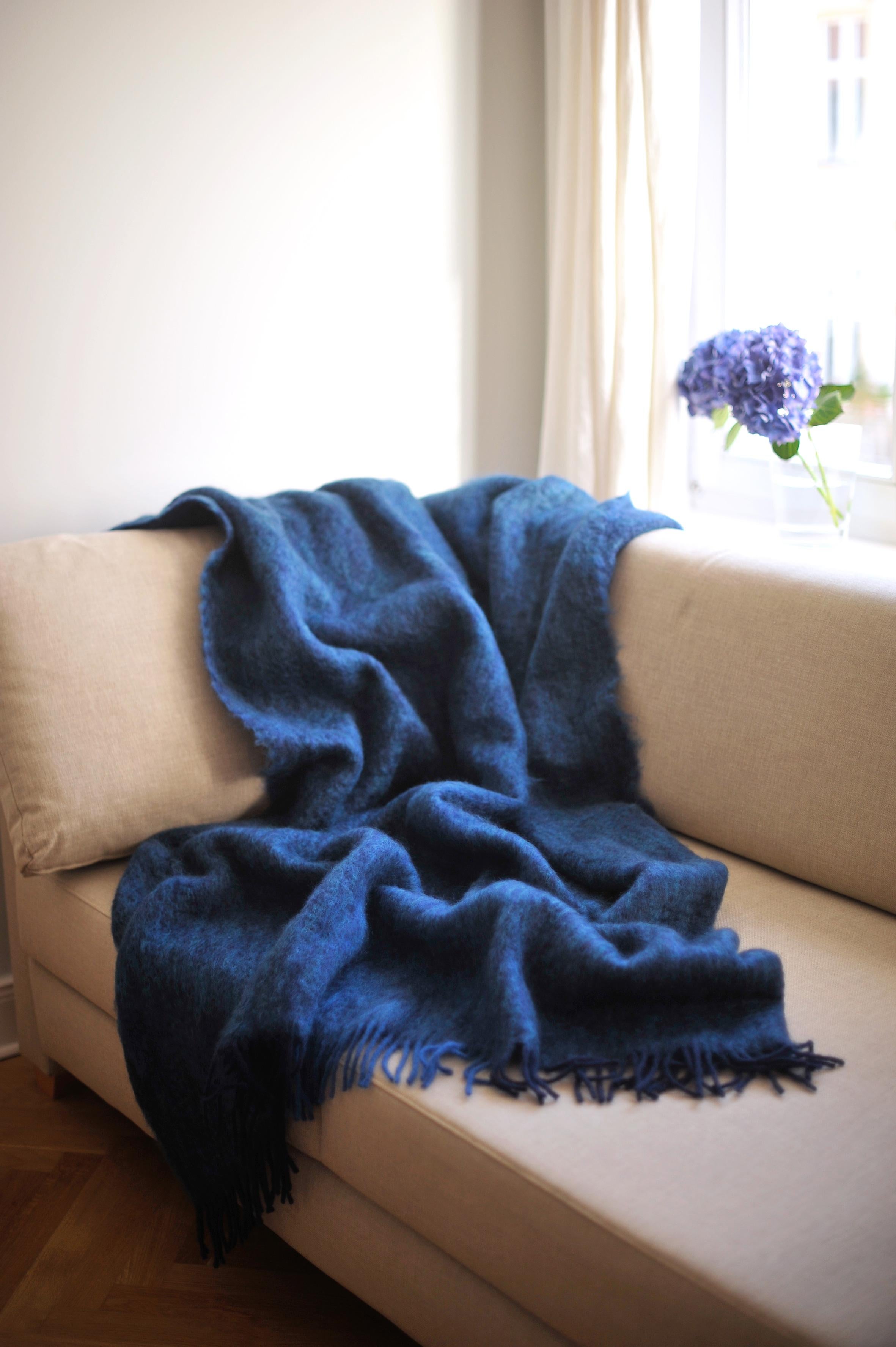 Entworfen in Berlin von Catharina Mende, gewebt aus 50% Mohair, 48% Wolle, 2% Polyamid in Spanien: Diese blaue schmeichelnde und wärmende flauschige Mohairdecke ist der perfekte Begleiter für jede Jahreszeit - ein unverzichtbares Lieblingsstück für