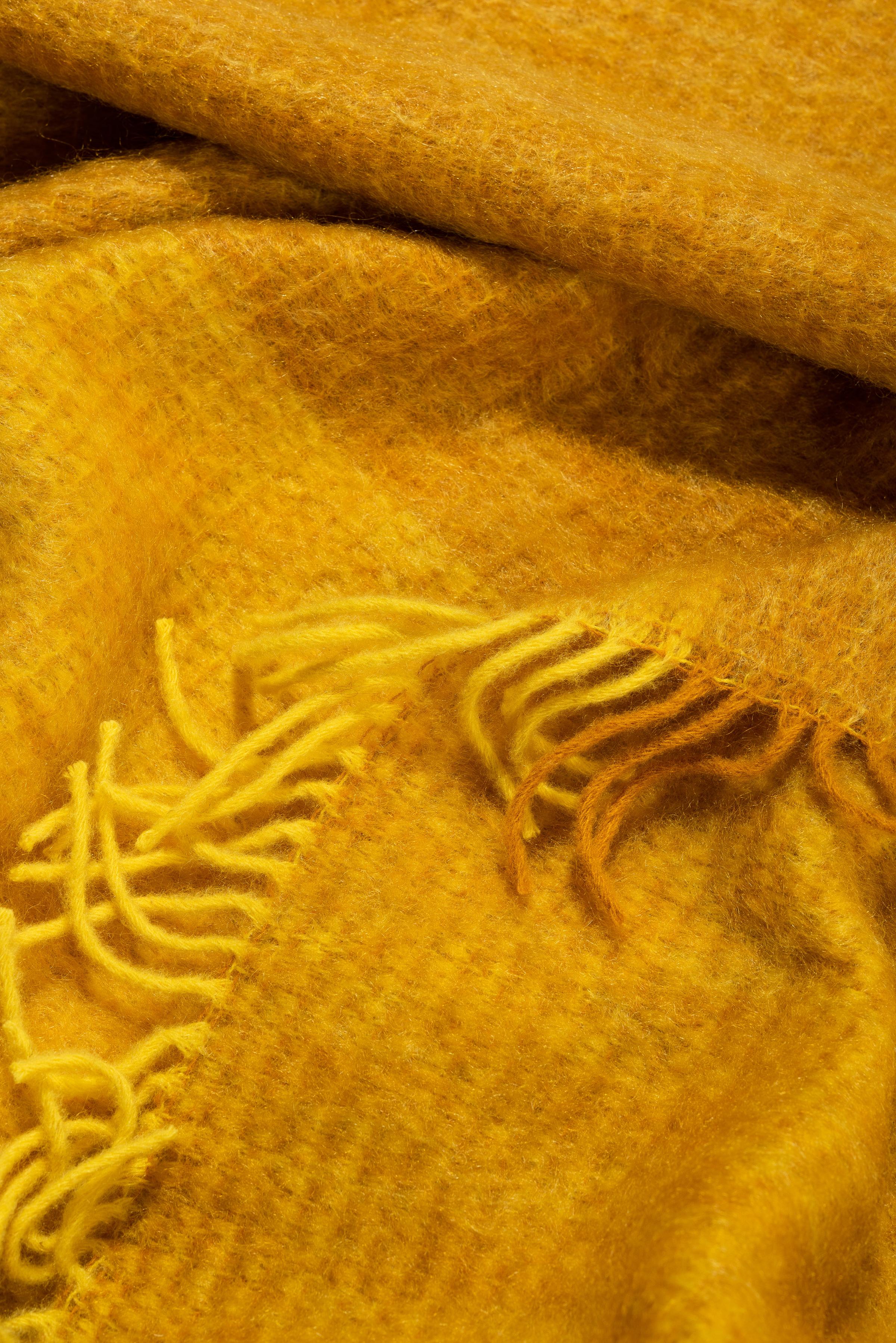 Entworfen in Berlin von Catharina Mende, gewebt aus 50% Mohair, 48% Wolle, 2% Polyamid in Spanien: Diese gelbe schmeichelnde und wärmende flauschige Mohairdecke ist der perfekte Begleiter für jede Jahreszeit - ein unverzichtbares Lieblingsstück für