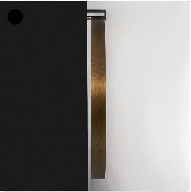 Miroir rond MOI avec une texture artisanale en laiton vieilli. 
Le support du cadre est en acier bronzé et peut être inséré dans le mur, dissimulant complètement les fixations, ou monté en surface, exposant les fixations.

Le cadre en laiton dépasse