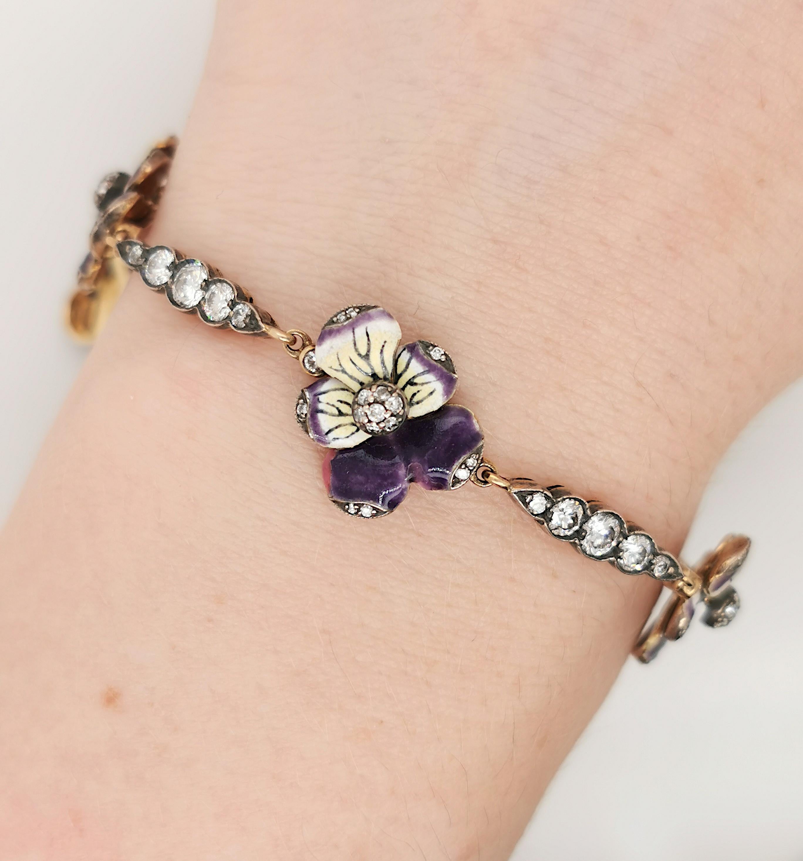 A Moira enamel and diamond pansy flower bracelet, with five purple and yellow enamel pansies, pavé set with round brilliant-cut diamonds, in the centre and petal edges, with a diamond to each side, with alternating panels of graduated, round