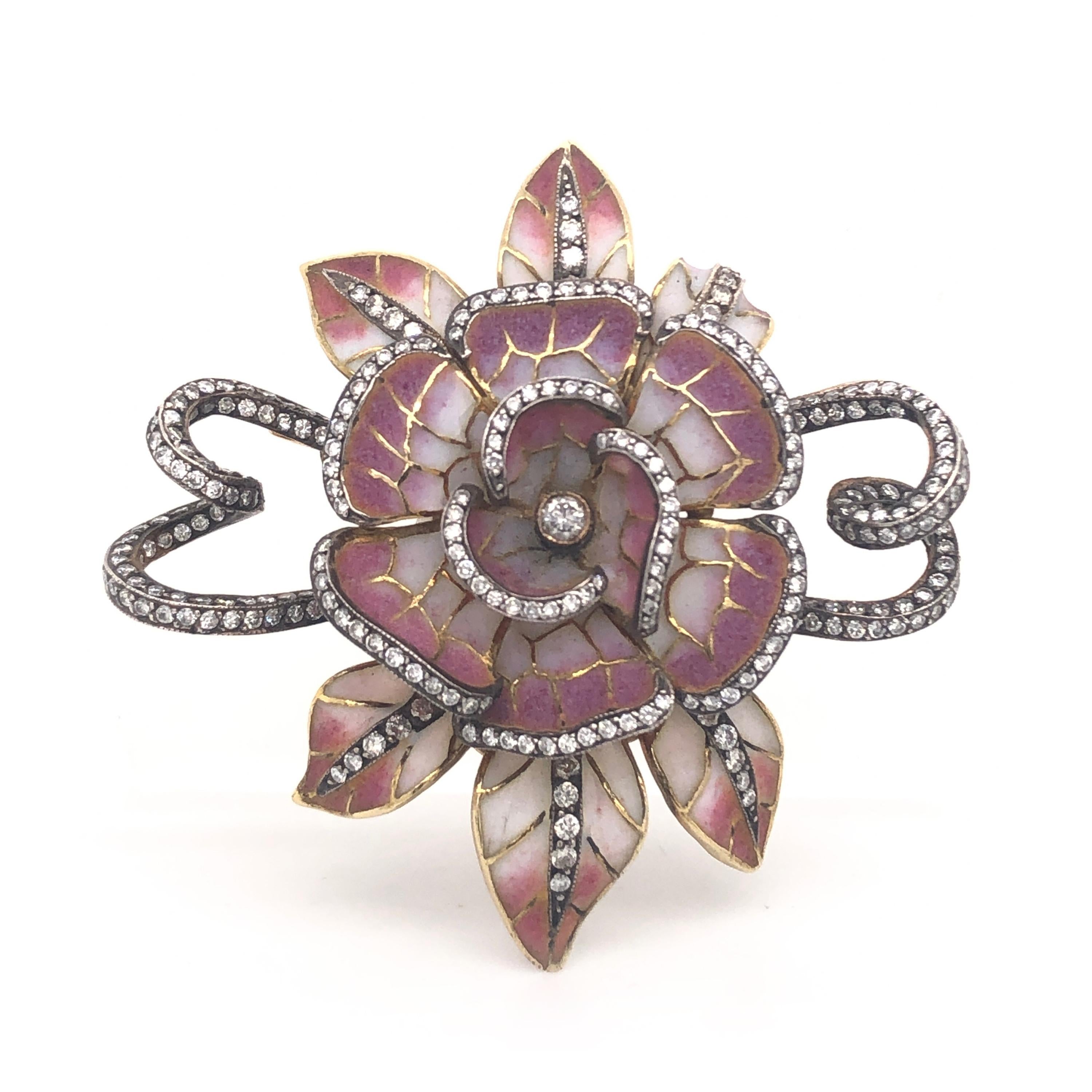 A Moira flower head brooch with pink and white plique à jour enamel and round brilliant-cut diamonds, with swirling ribbon, pavé set with diamonds. Signed Moira, numbered 5102.