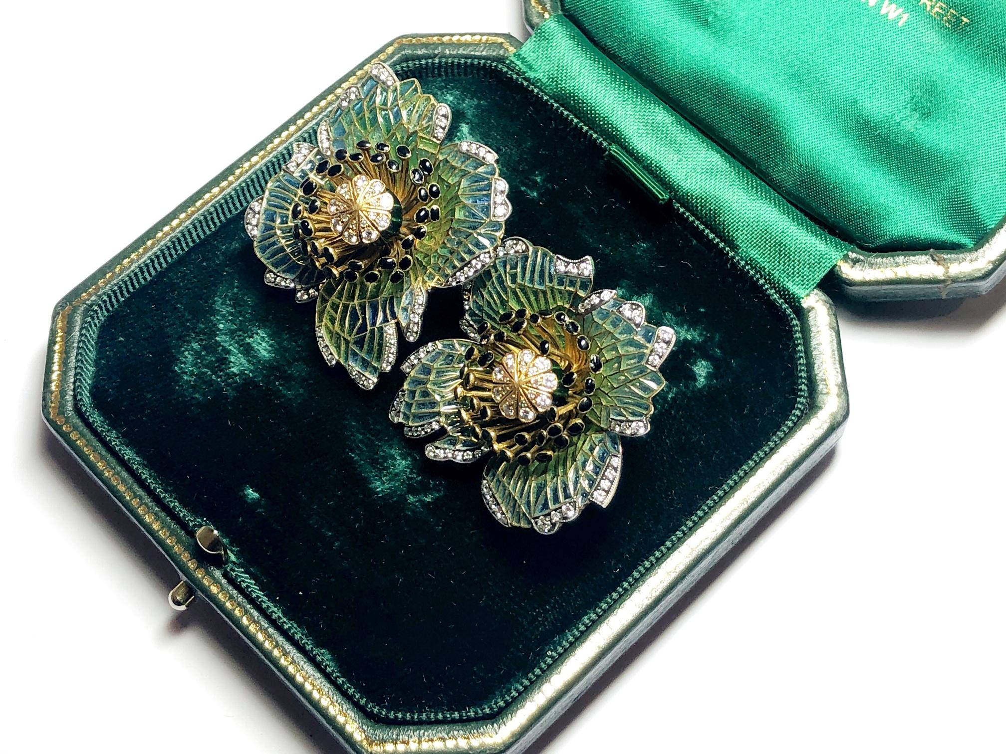 A pair of Moira poppy earrings, with blue to green plique à jour enamel petals, black enamel anthers, with a green enamelled pistil, with set with round brilliant-cut diamonds, mounted in gold, with silver settings. Signed Moira, numbered 5512, with