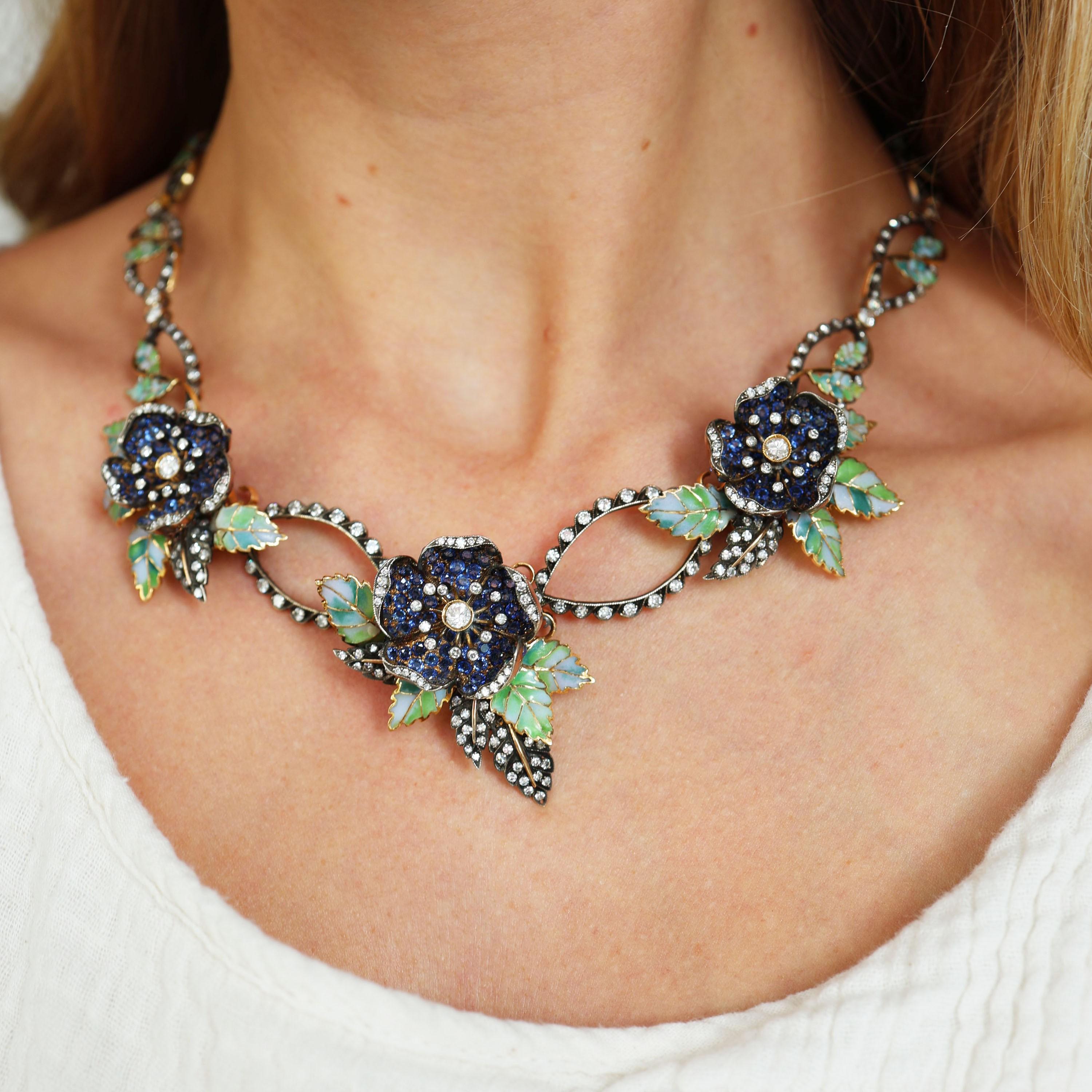 Un collar de flores Moira de zafiros, diamantes, esmalte, oro y plata, con tres flores de una sola rosa, en la parte delantera del collar, engastadas con pavé de zafiros y diamantes talla antigua y talla ocho, en los bordes de los pétalos, con hojas