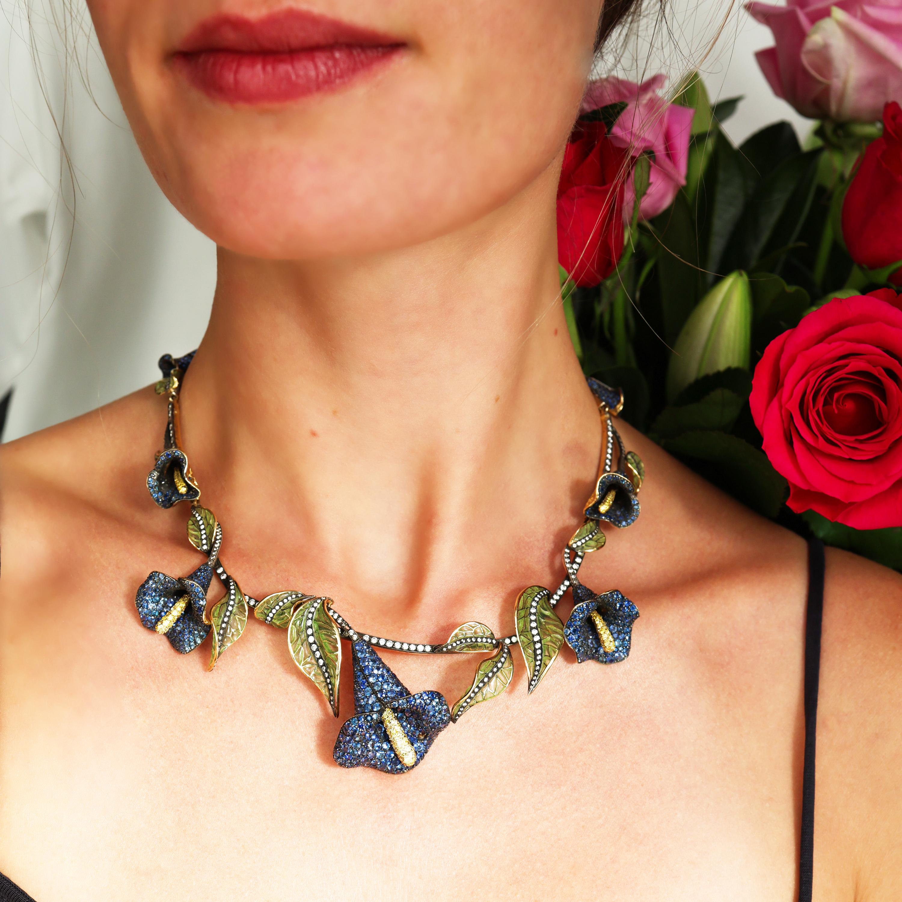 A modern, sapphire and diamond calla lily floral wreath necklace, which is part of the MOIRA Collection, featuring calla lilies, in a graduating wreath, which are pavé set with sapphires and yellow diamond set spadices, with stems which are set with