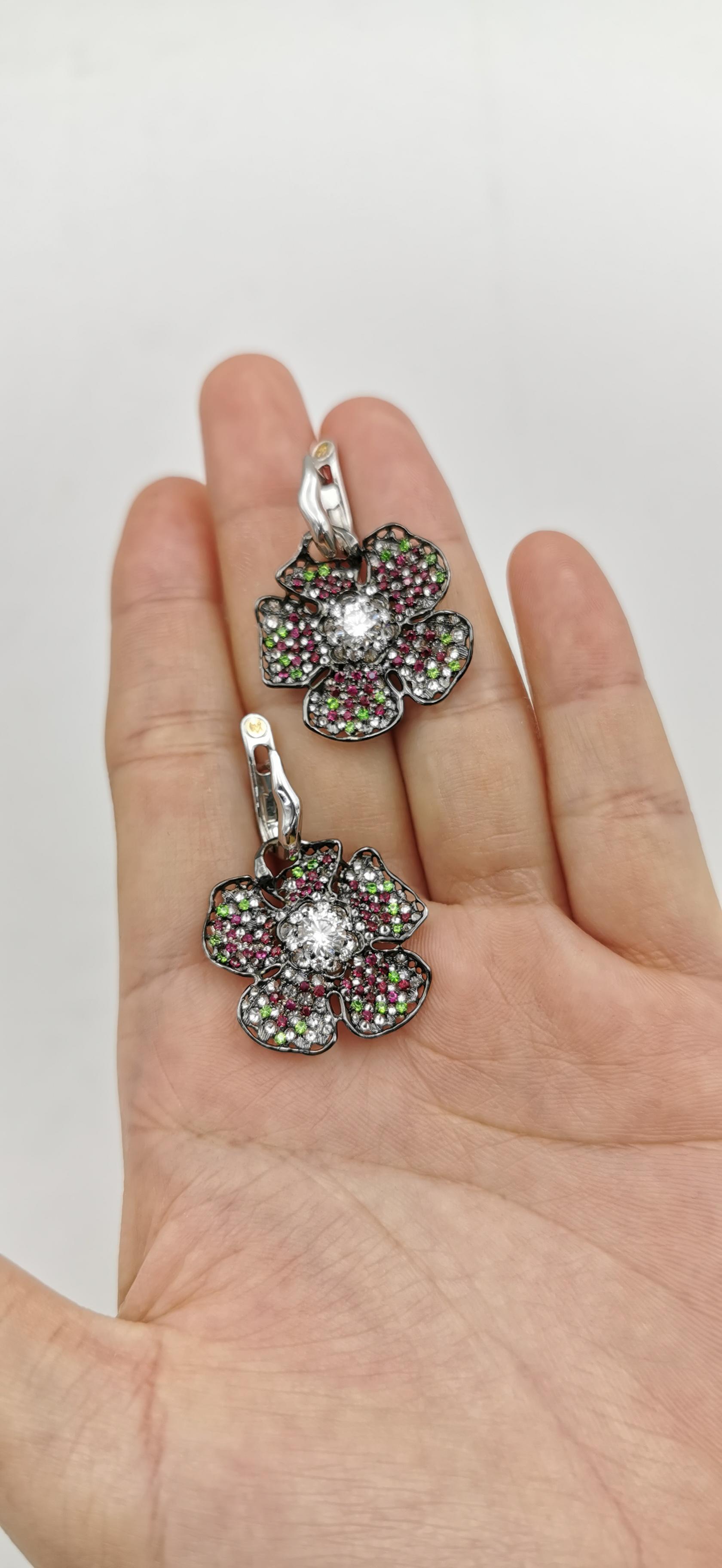 Over 3.5 ct diamonds, radiant demantoid garnet and  passionate rubies  make a great harmony on a  poppy flower design cocktail earrings.  

Stones mounted upside down , the flower petals gives unusual luminescence.  
Rubies shining on the blackened