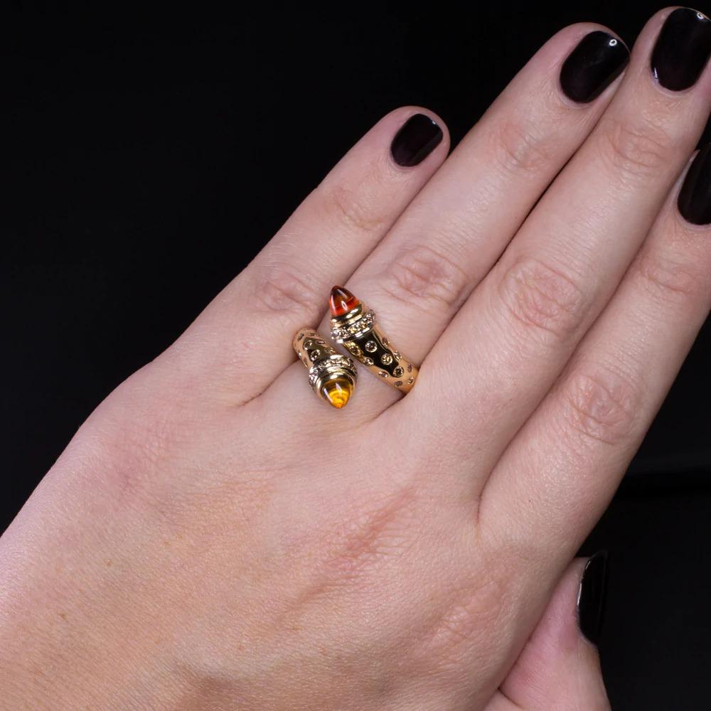 diamond ring features a pair of domed citrine accented by flush set champagne diamonds. The bypass design is very unique, and the play of color between the citrine, diamonds, and buttery 18k gold creates a bold, luxurious aesthetic. Weighing 11.6