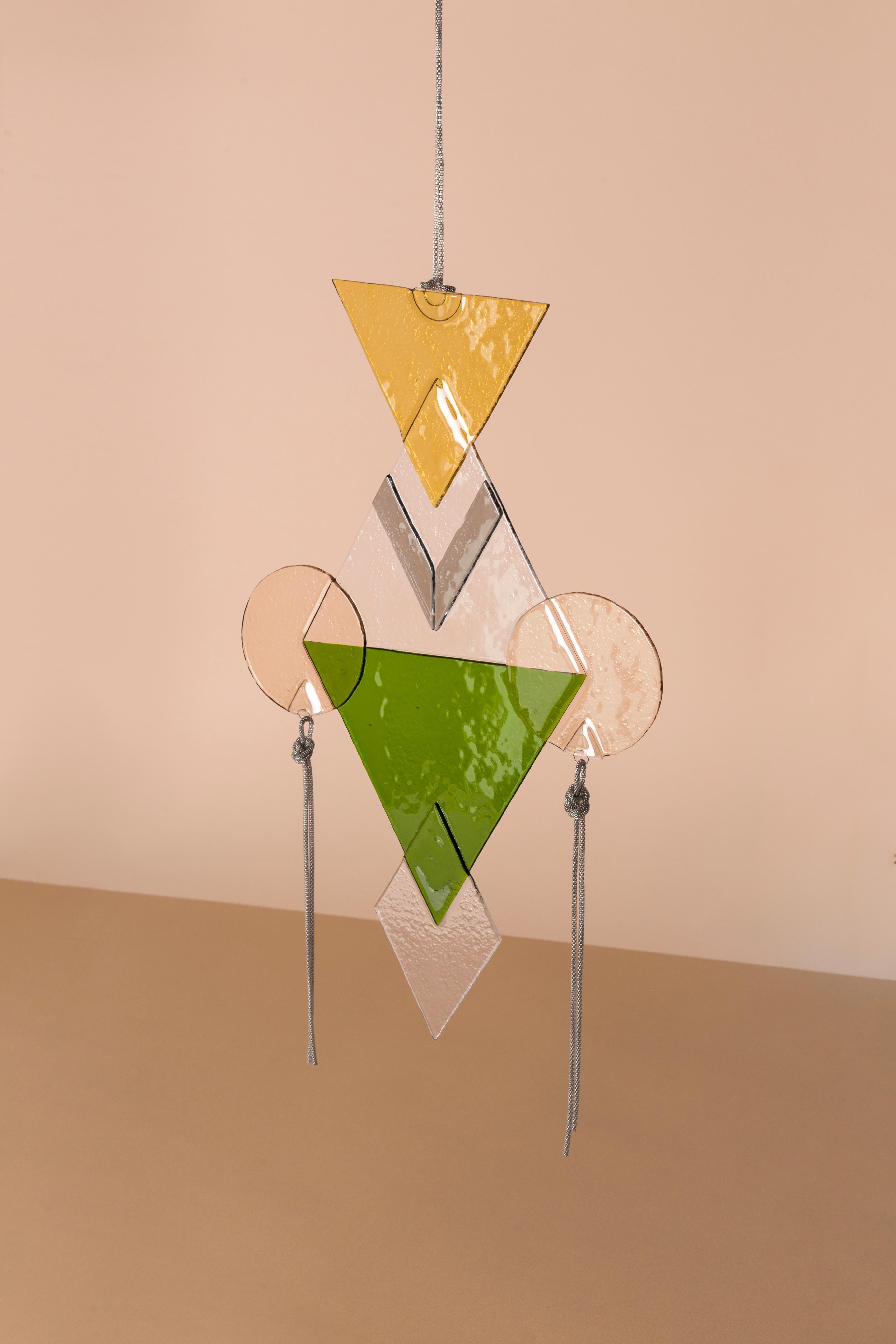 Mojo Amulet Silver by Serena Confalonieri
Dimensions: 30 x 48 x 1 cm
Materials: Glass fusion, decorative aluminum chains
Glass colors: Transparent, yellow, grey, pink, green
Chain color: Silver

Artisanal glass fusion with decorative aluminium
