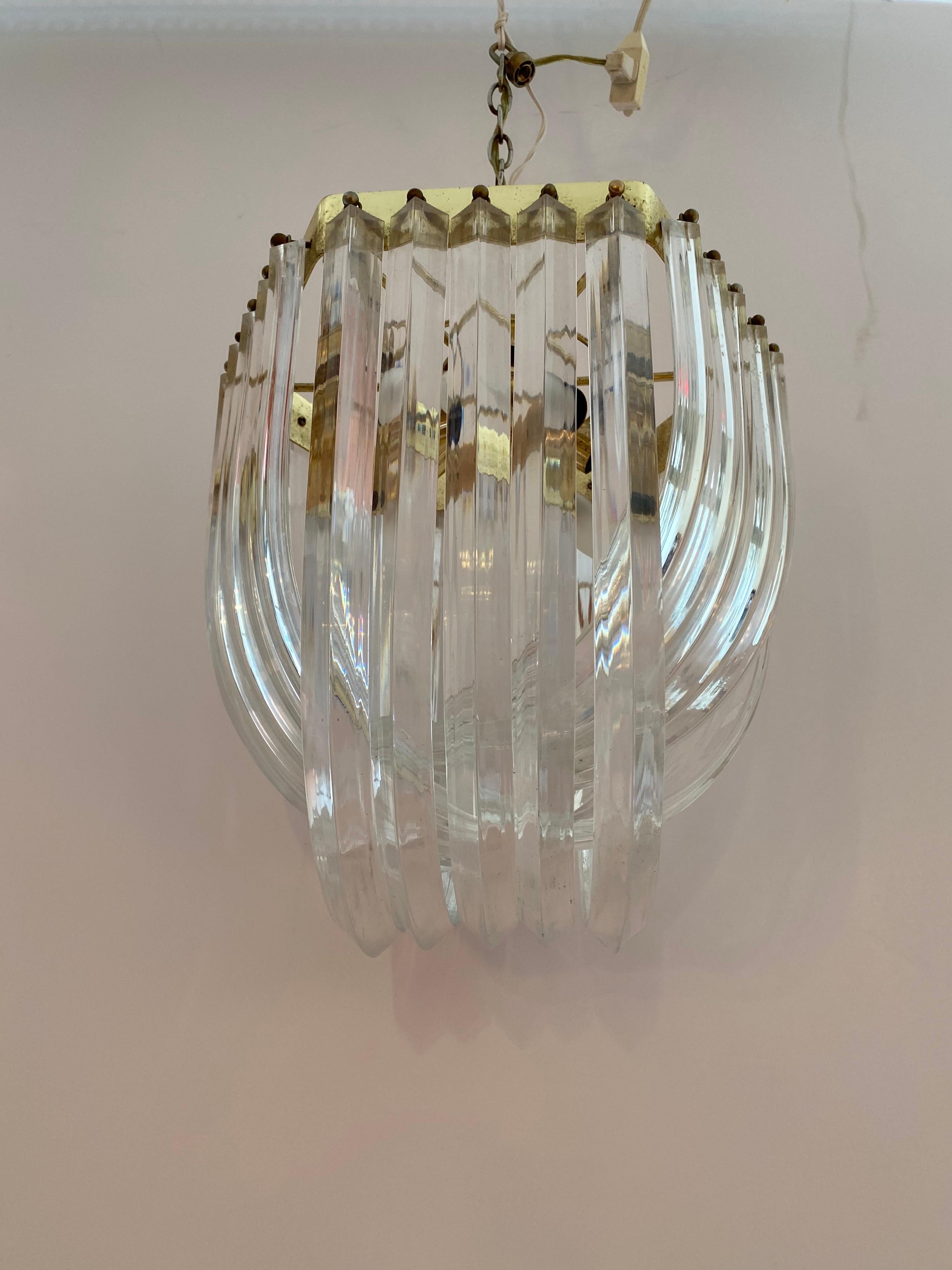 Molded Lucite fixture with cascading bands. Brass frame holds 