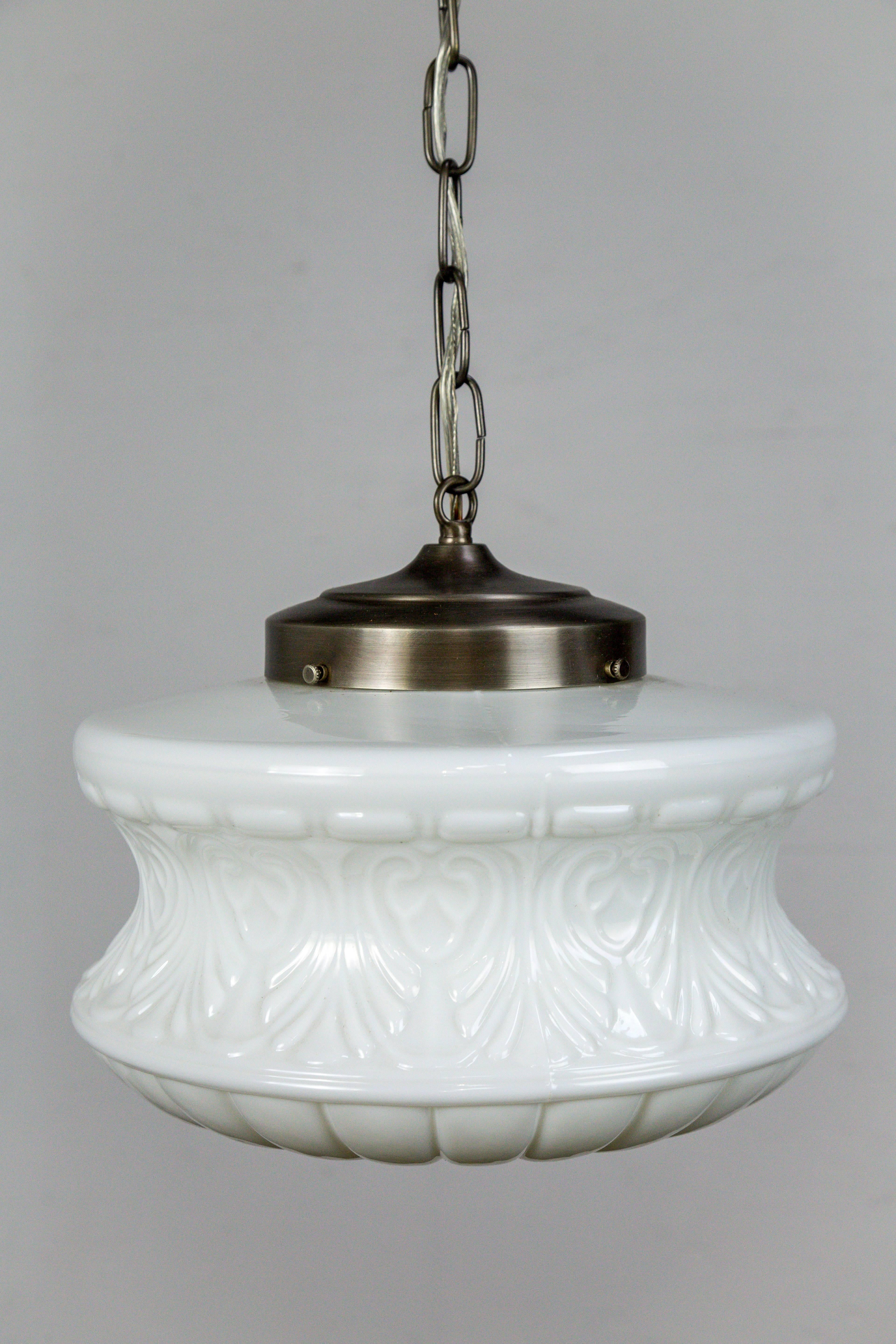 This antique, molded milk glass has a beautiful shape with an acorn and palmette motif. It has been fashioned with a new, brushed nickel tinted brass shade holder, chain, and canopy. The canopy has a lovely floral shape that compliments the design